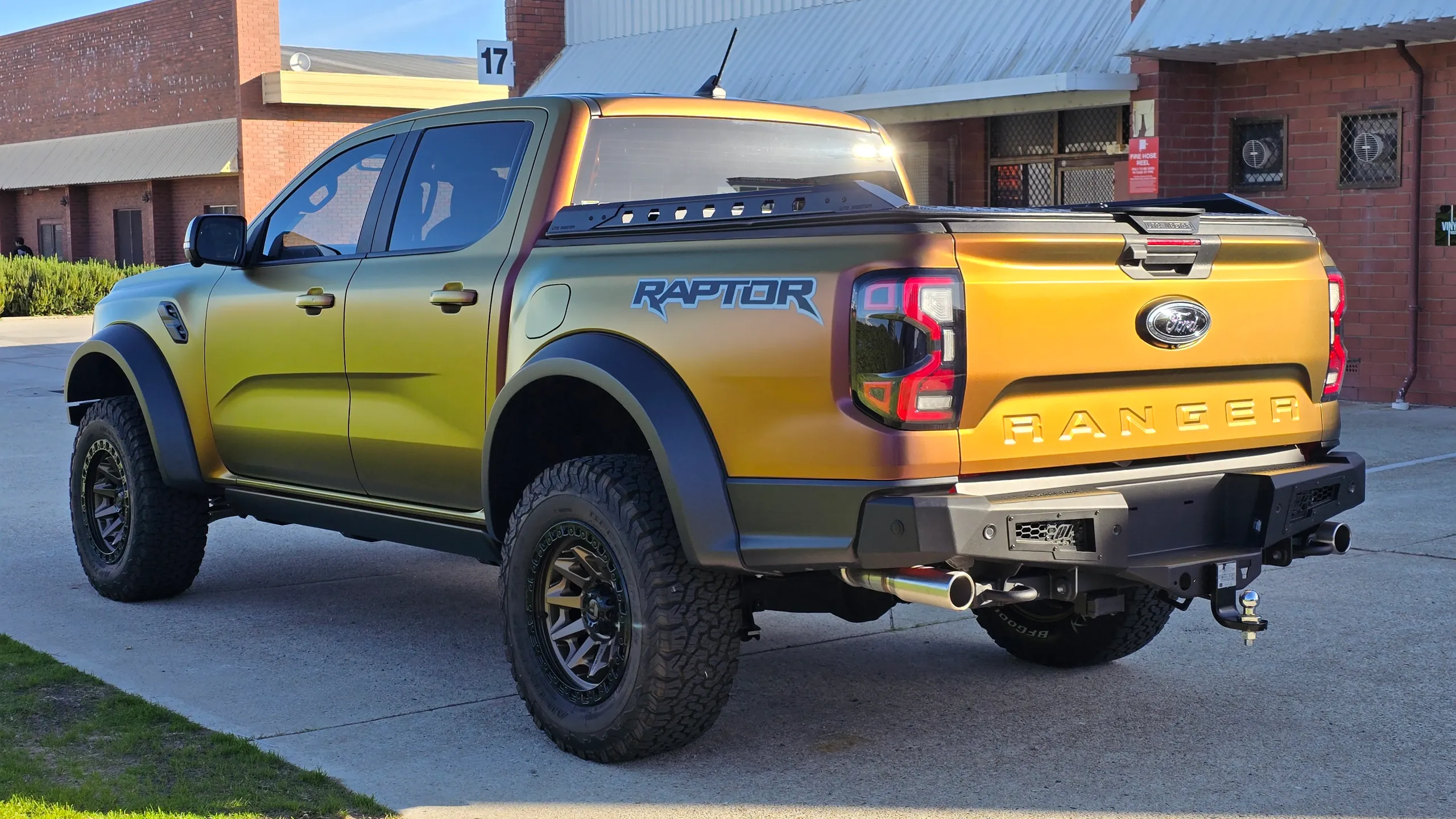 Gold and green tones across the Ford Ranger Raptor tailgate and doors in sunlight
