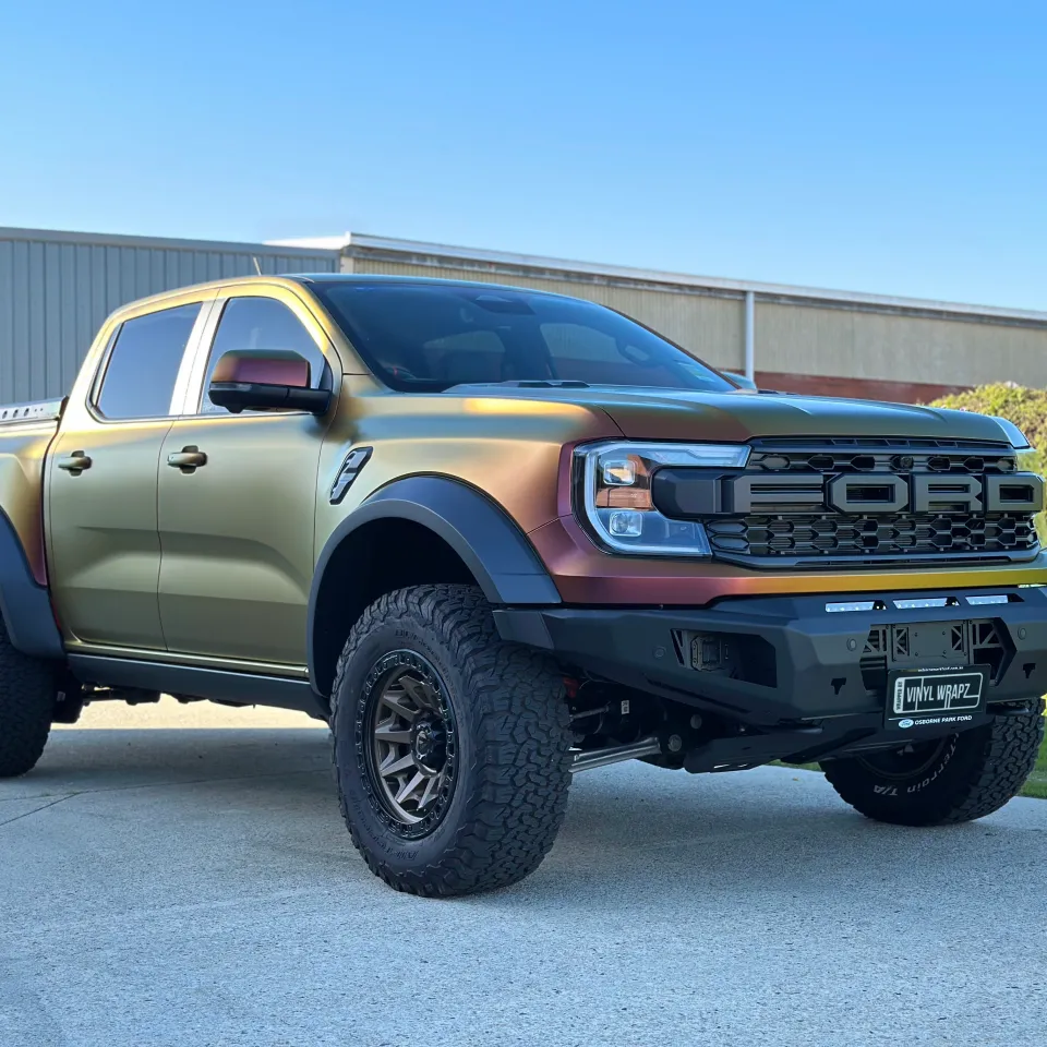 Ford Ranger Raptor with a satin colour-shift wrap, off-road tyres and black front bar outdoors