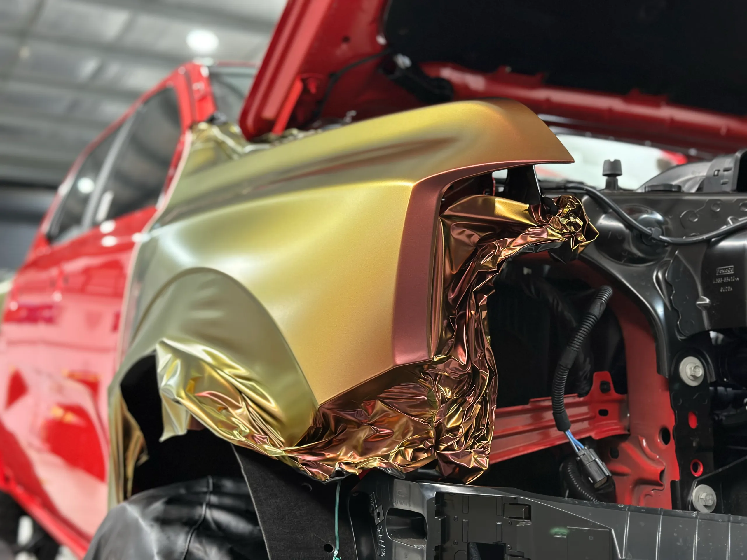Colour-shift film partly fitted to a red Ford Ranger Raptor front guard with the headlight removed