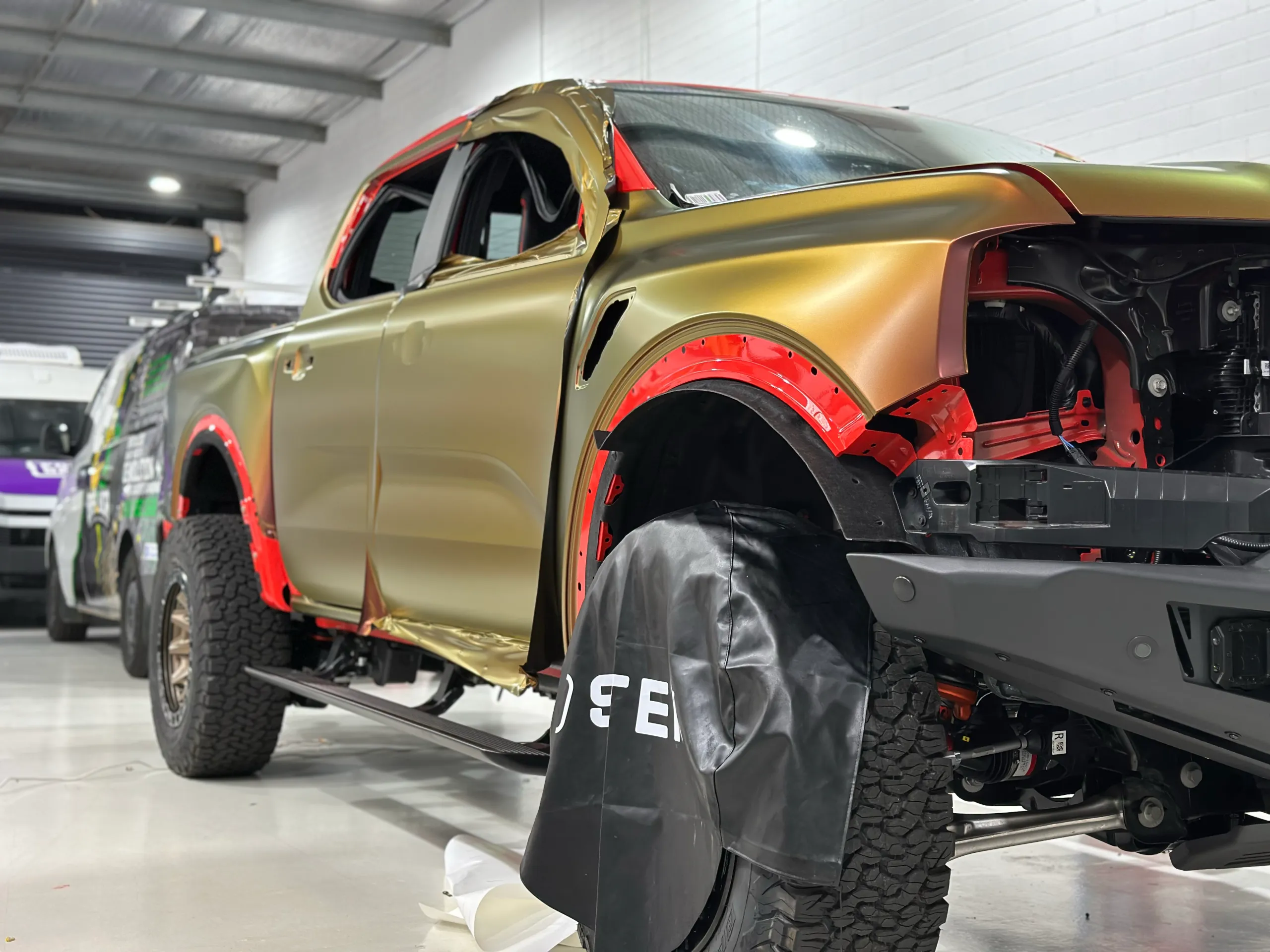 Colour-shift film partly fitted across the Ford Ranger Raptor doors and front guard in the workshop