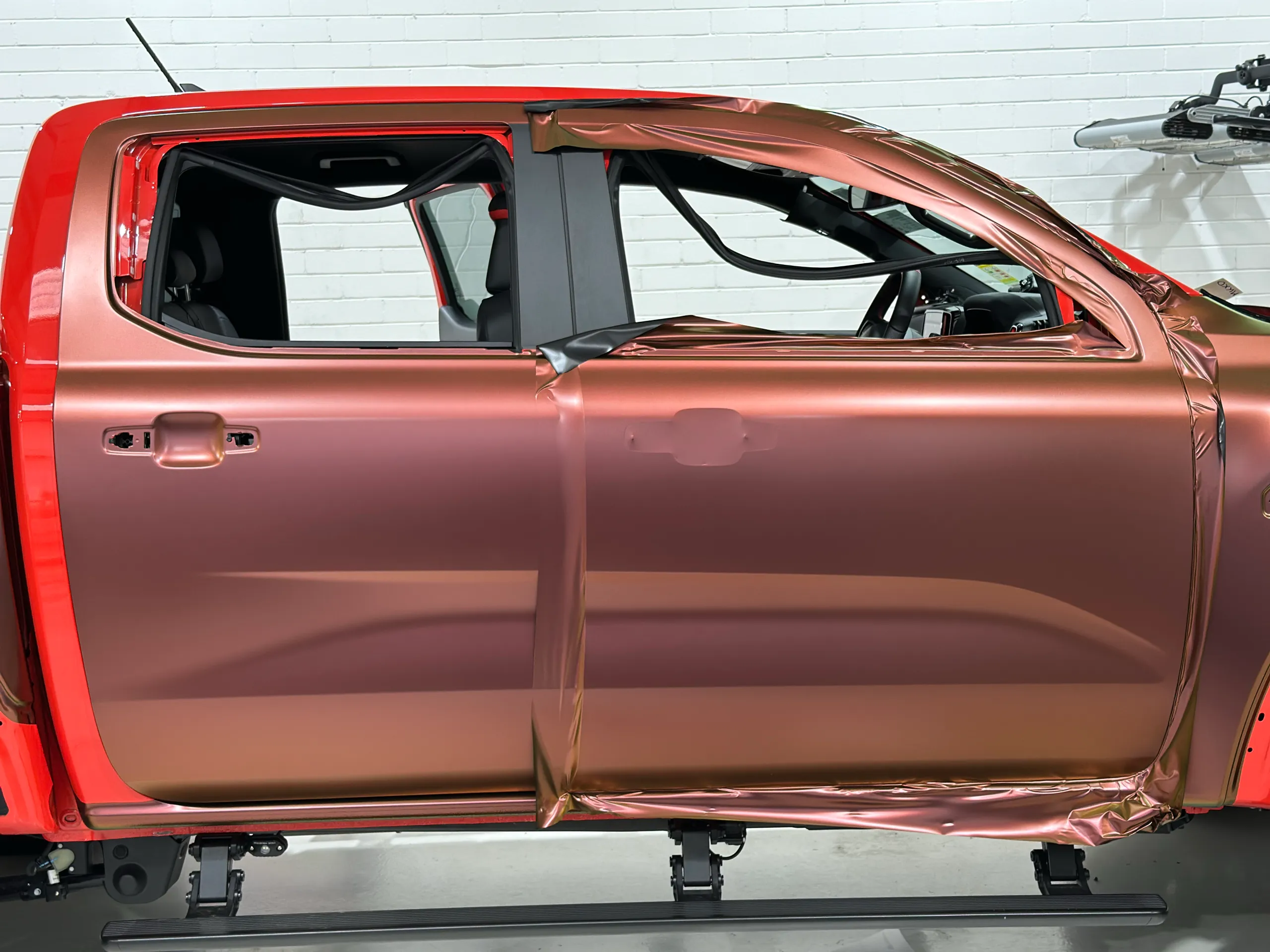Copper-toned film being fitted to the Ford Ranger Raptor doors with handles and window trim removed