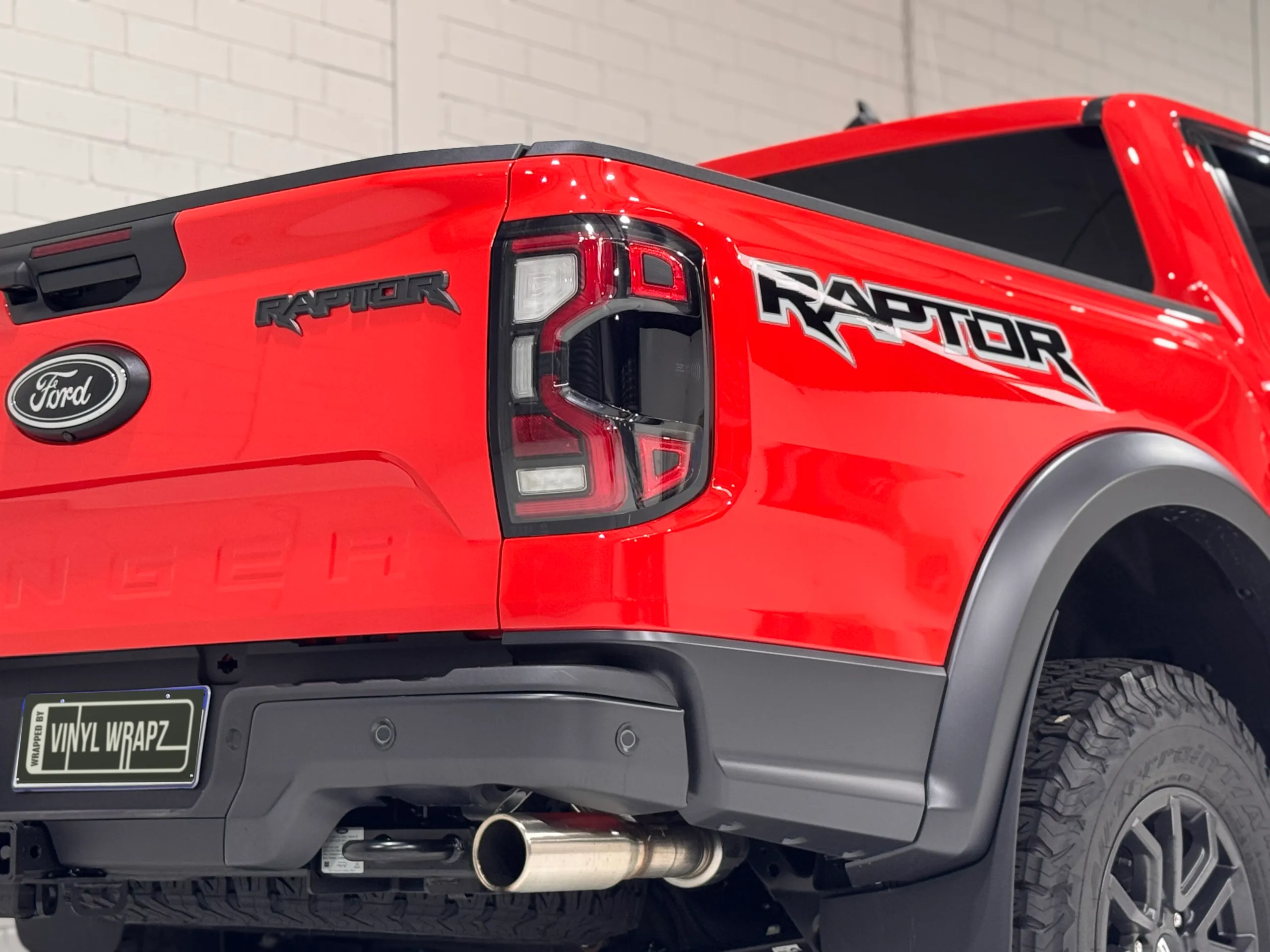 Low rear-quarter view of the red Ford Ranger Raptor tailgate and rear wheel