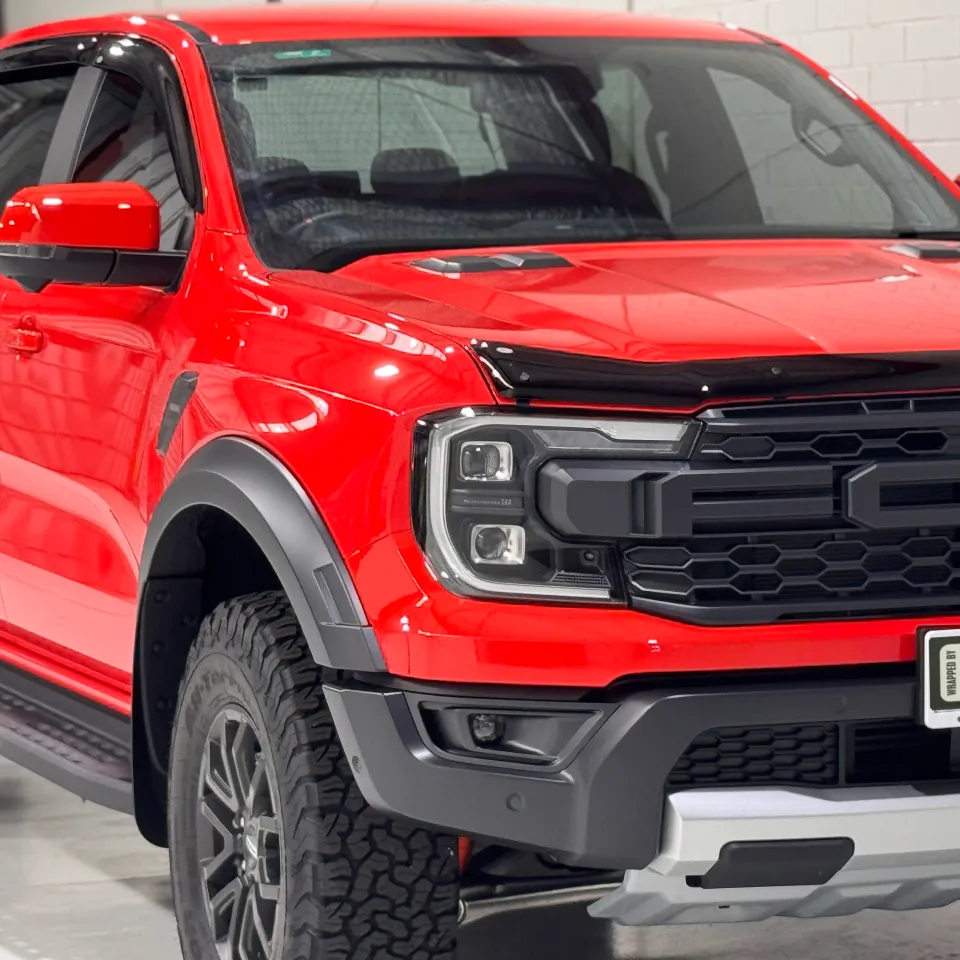Gloss red Ford Ranger Raptor viewed from the front quarter in the workshop
