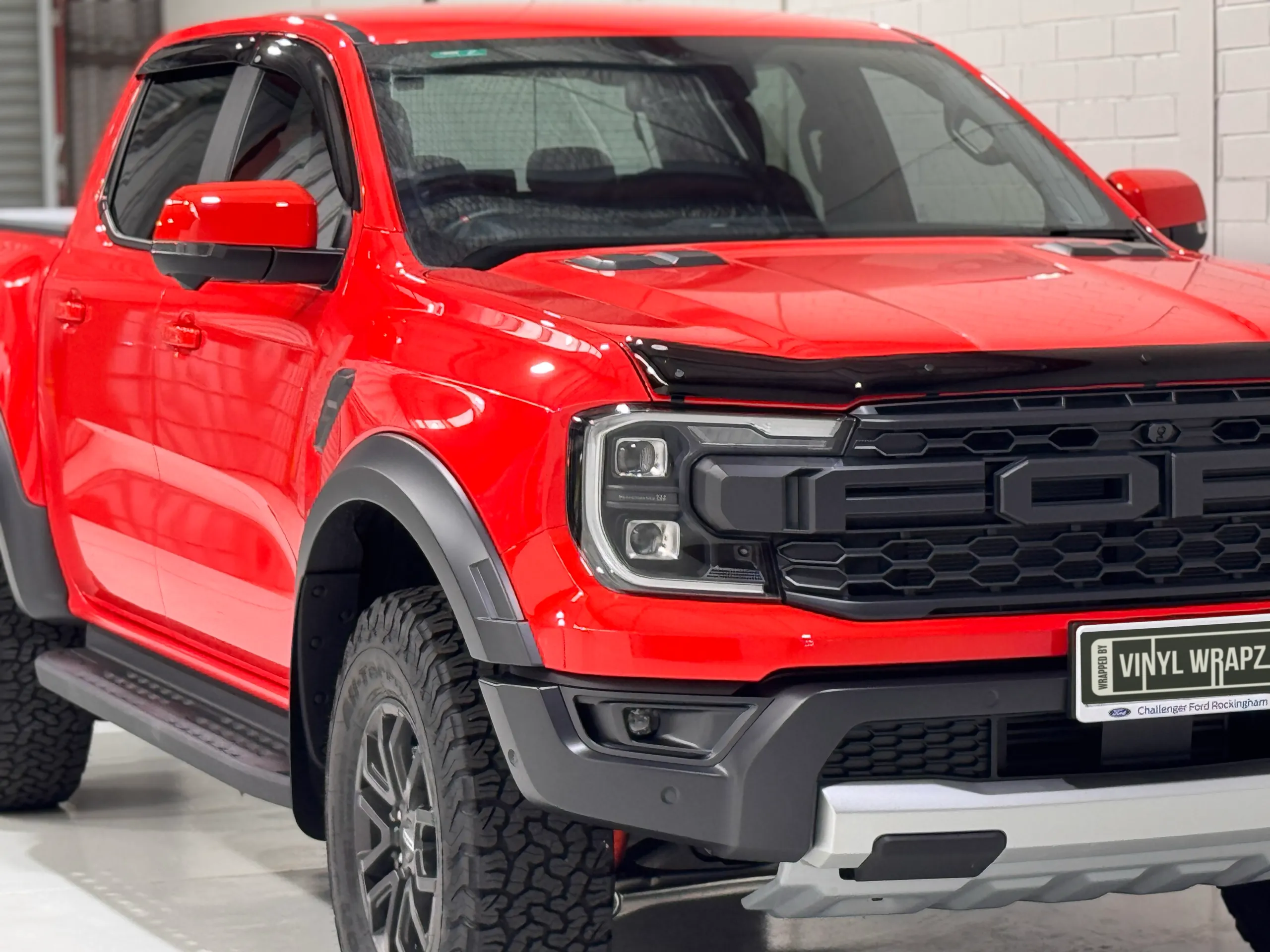 Gloss red Ford Ranger Raptor viewed from the front quarter in the workshop