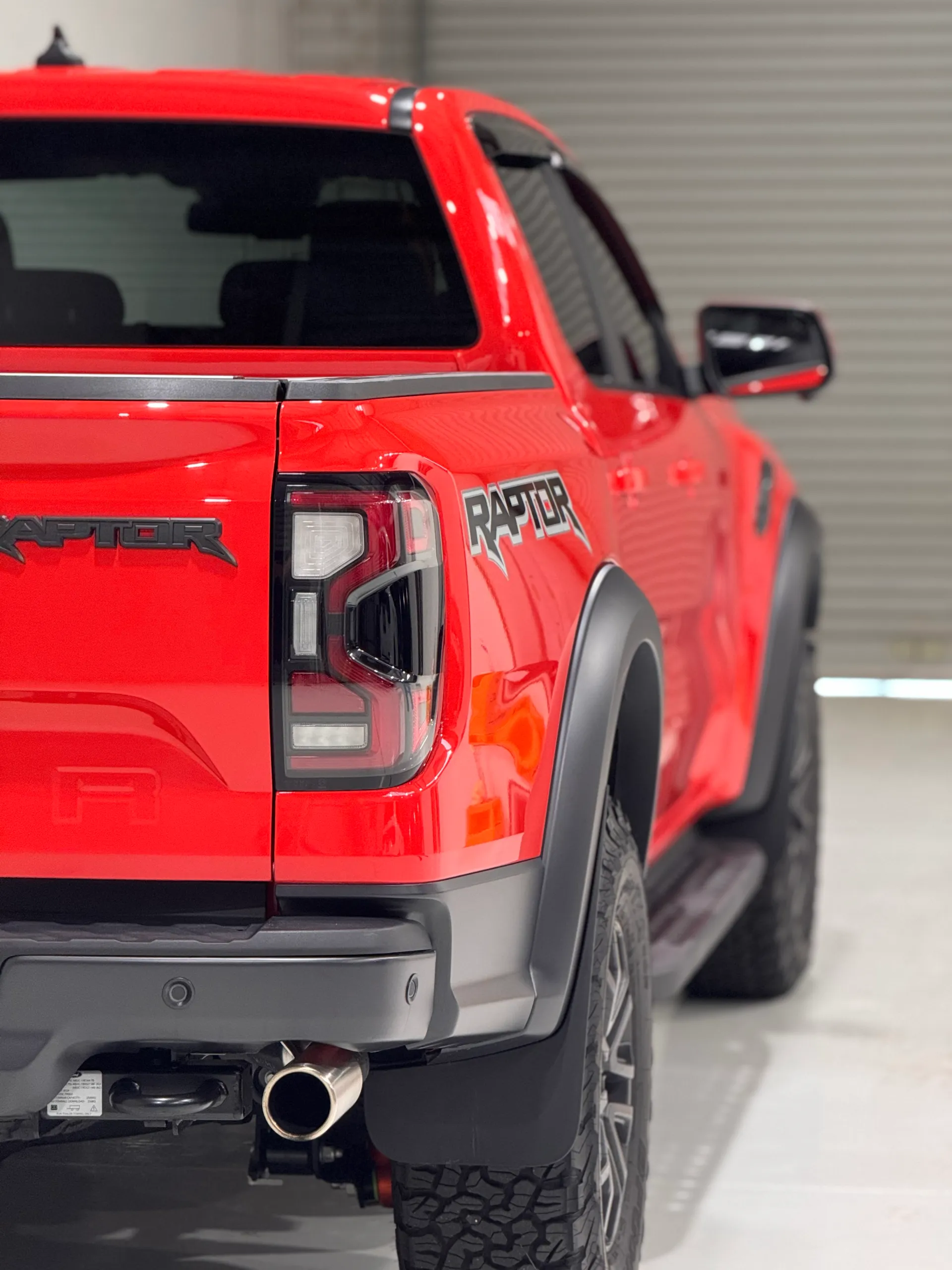 Rear-corner view along the red Ford Ranger Raptor tray and doors