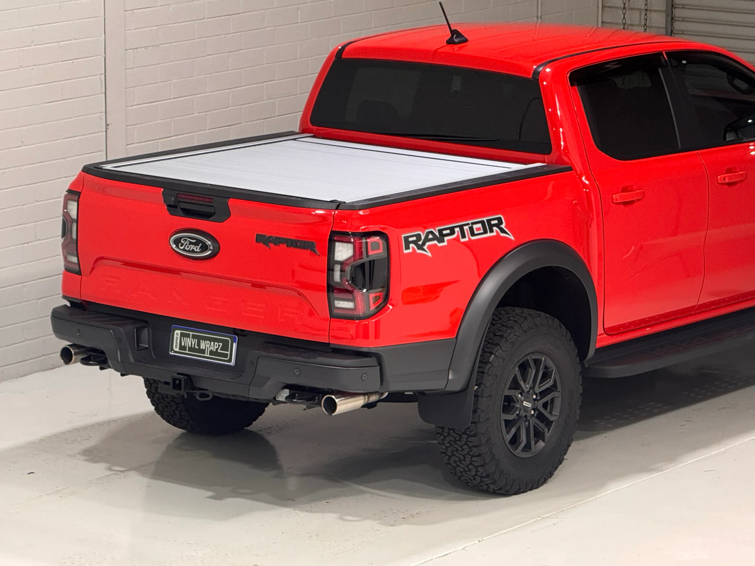 Elevated rear-quarter view of the red Ford Ranger Raptor with a silver tray cover