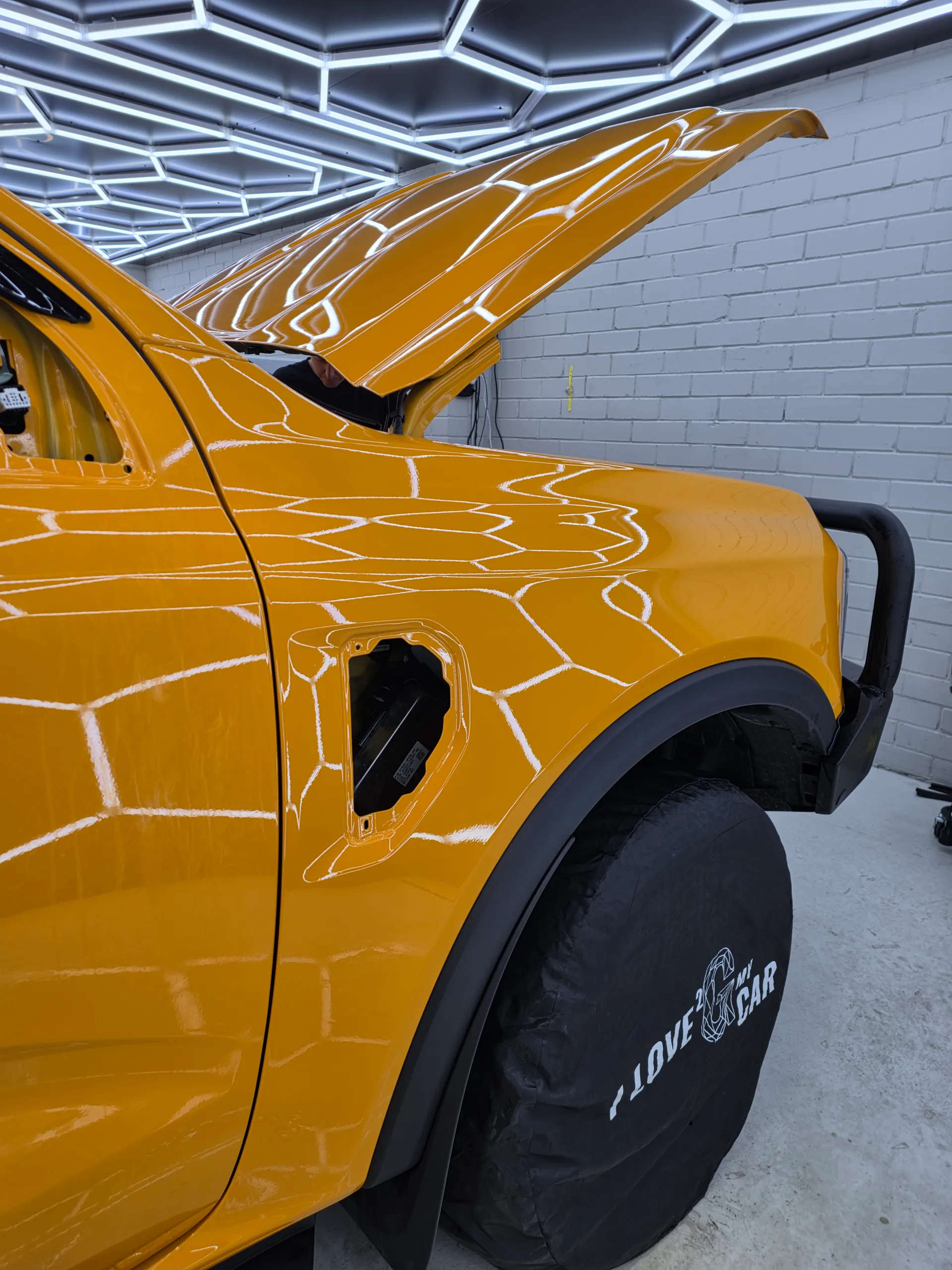 Orange Ford Ranger front guard during film work, with the bonnet open and side trim removed