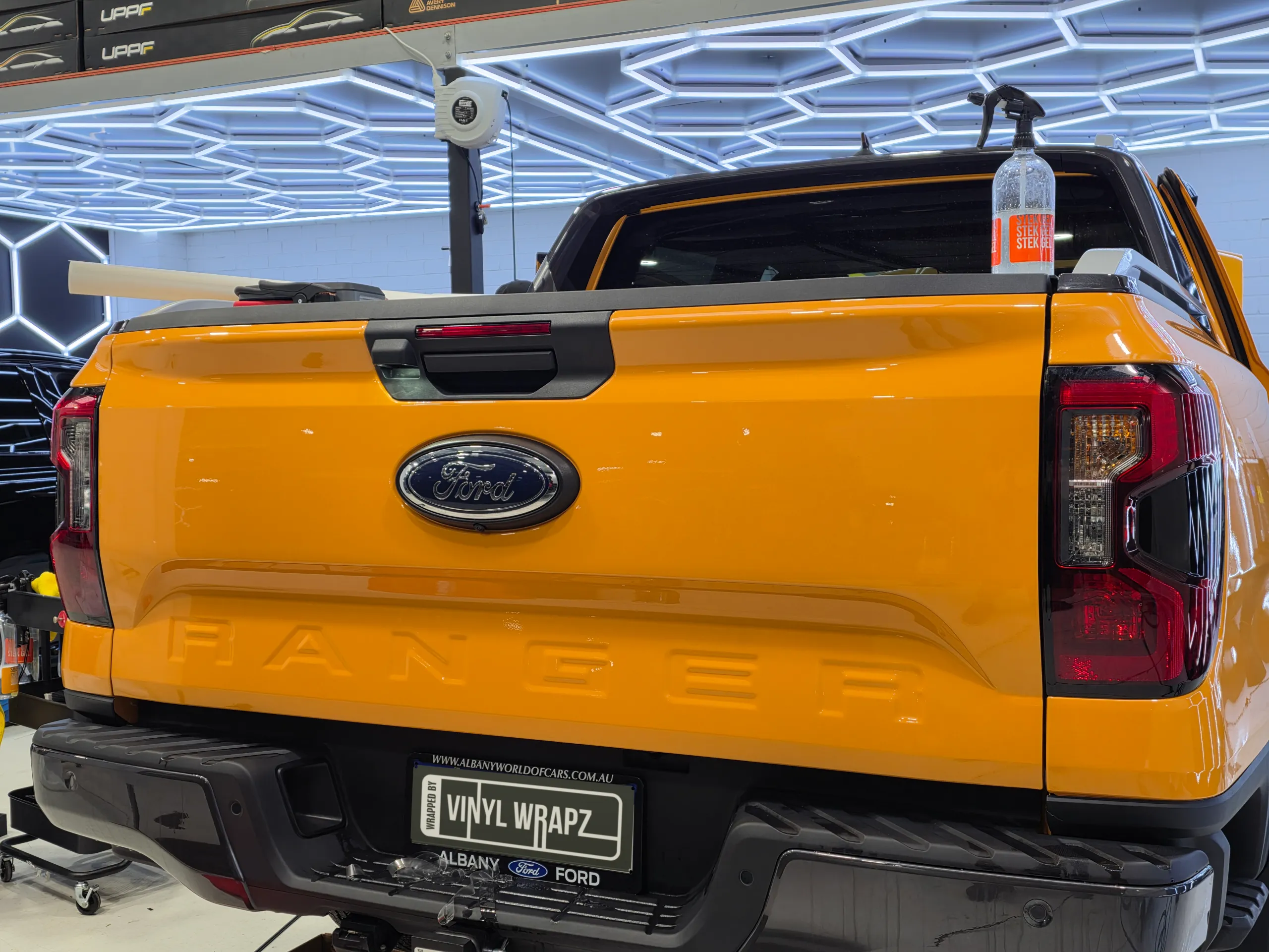 Ford Ranger tailgate during film installation, with a spray bottle and film roll on the tub