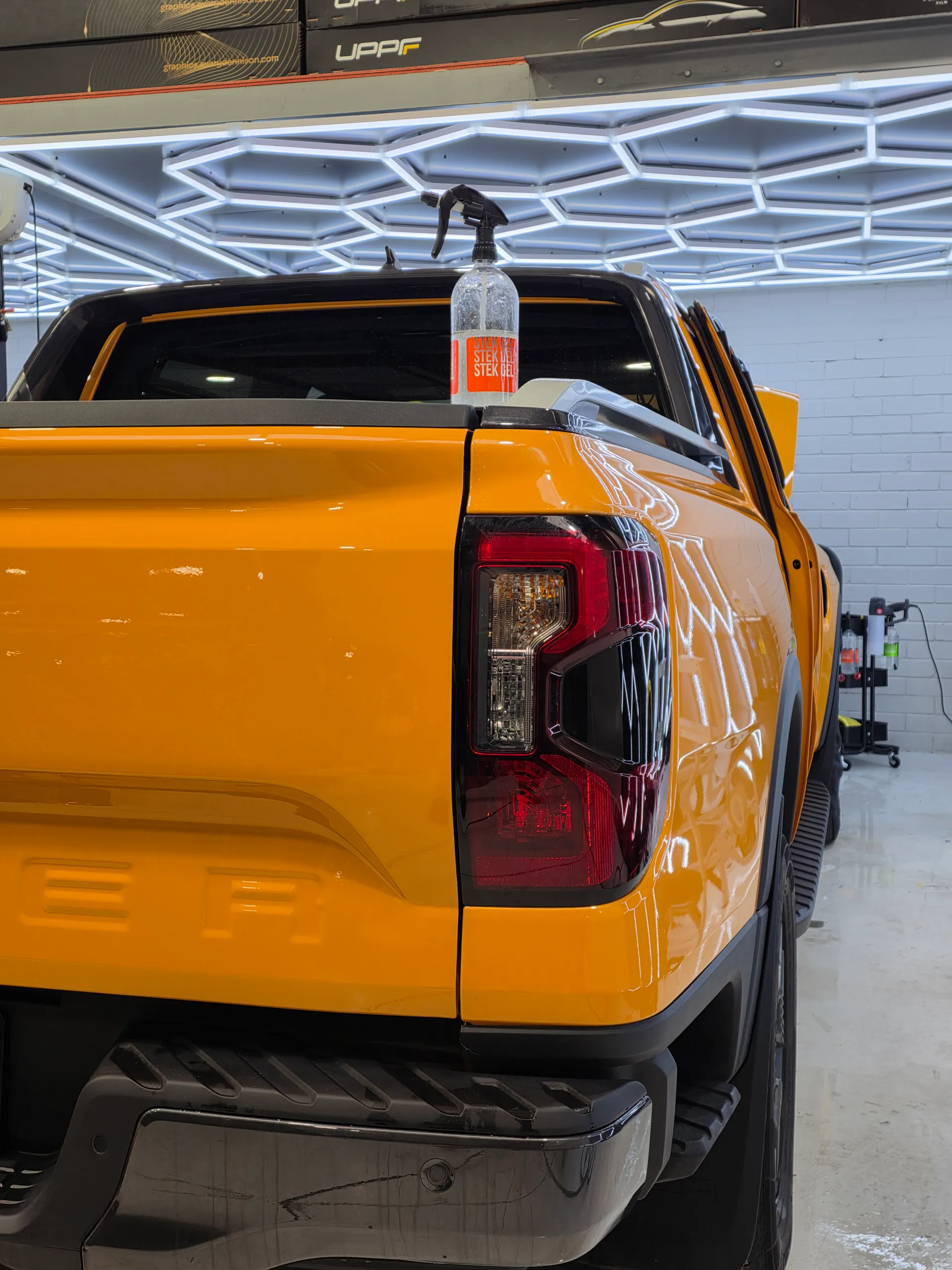Orange Ford Ranger rear corner during film installation, showing the tail light and tub side