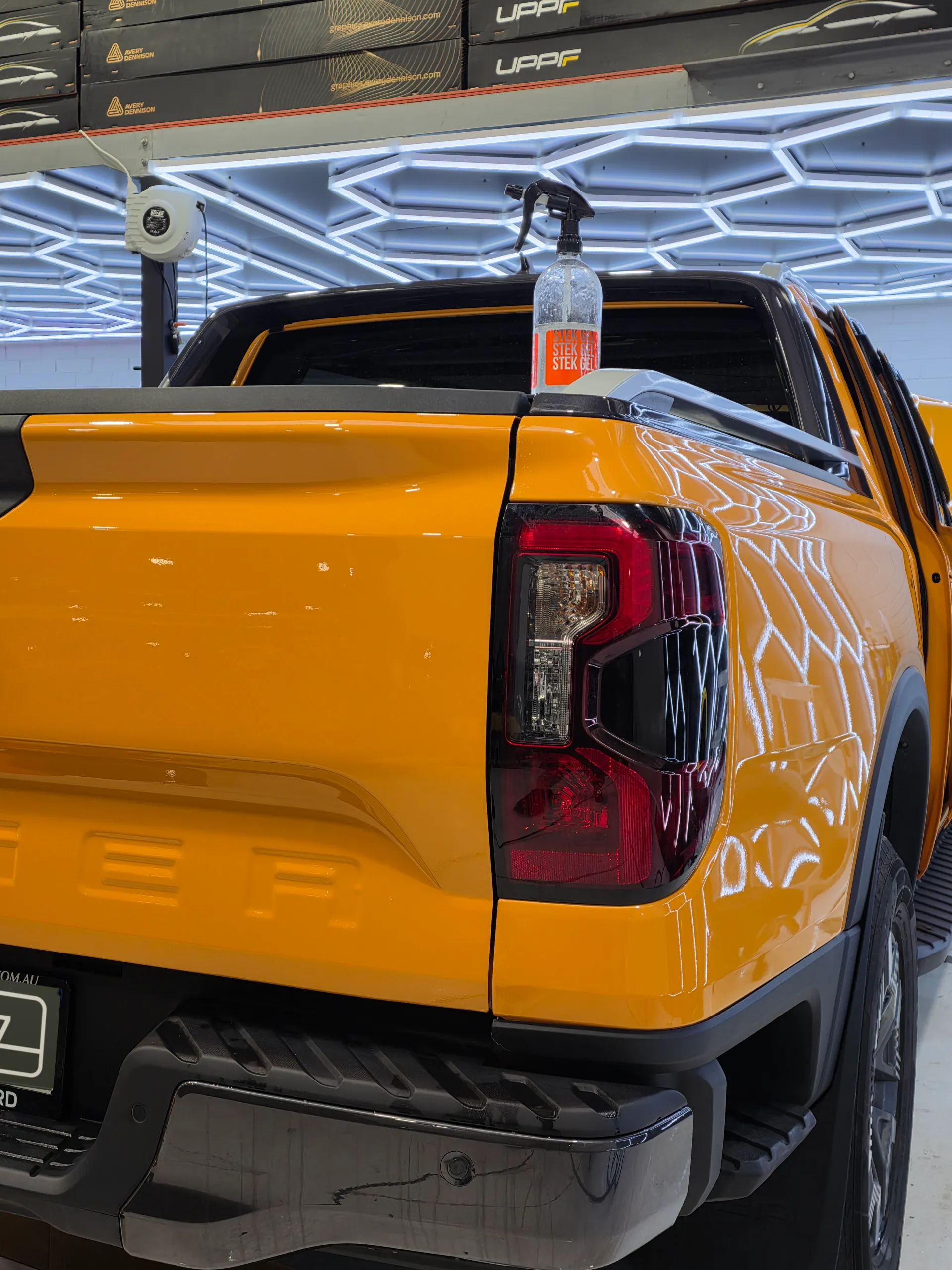 Orange Ford Ranger rear light and tub side beneath reflected workshop lights during film work