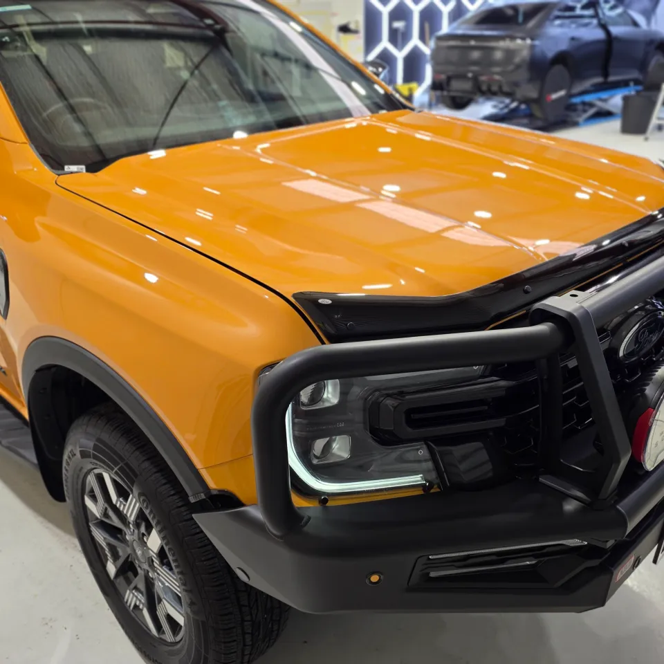 Orange Ford Ranger Wildtrak PHEV front quarter and bull bar under workshop lights