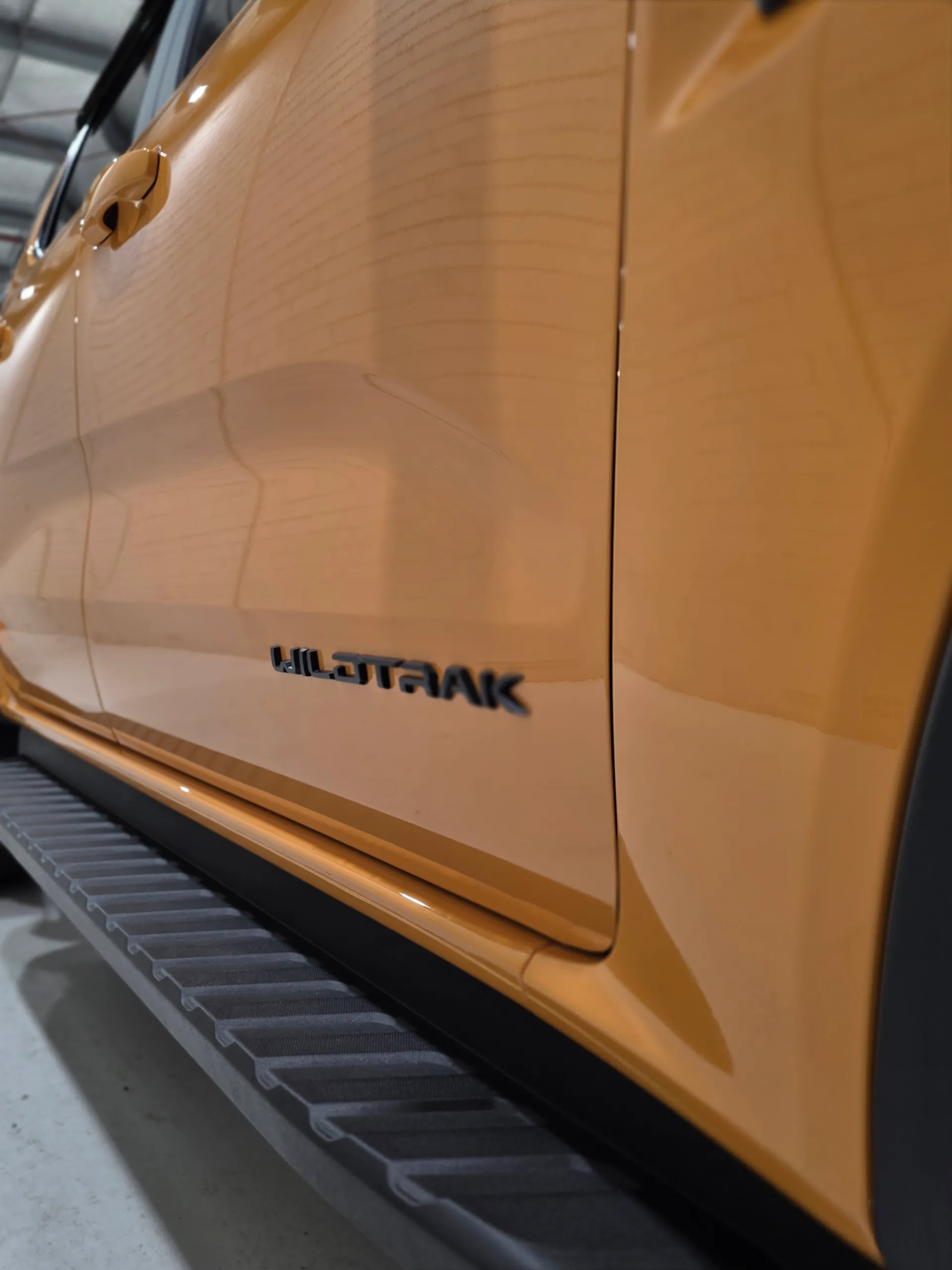 Wildtrak badge on an orange Ford Ranger door, above the black side step