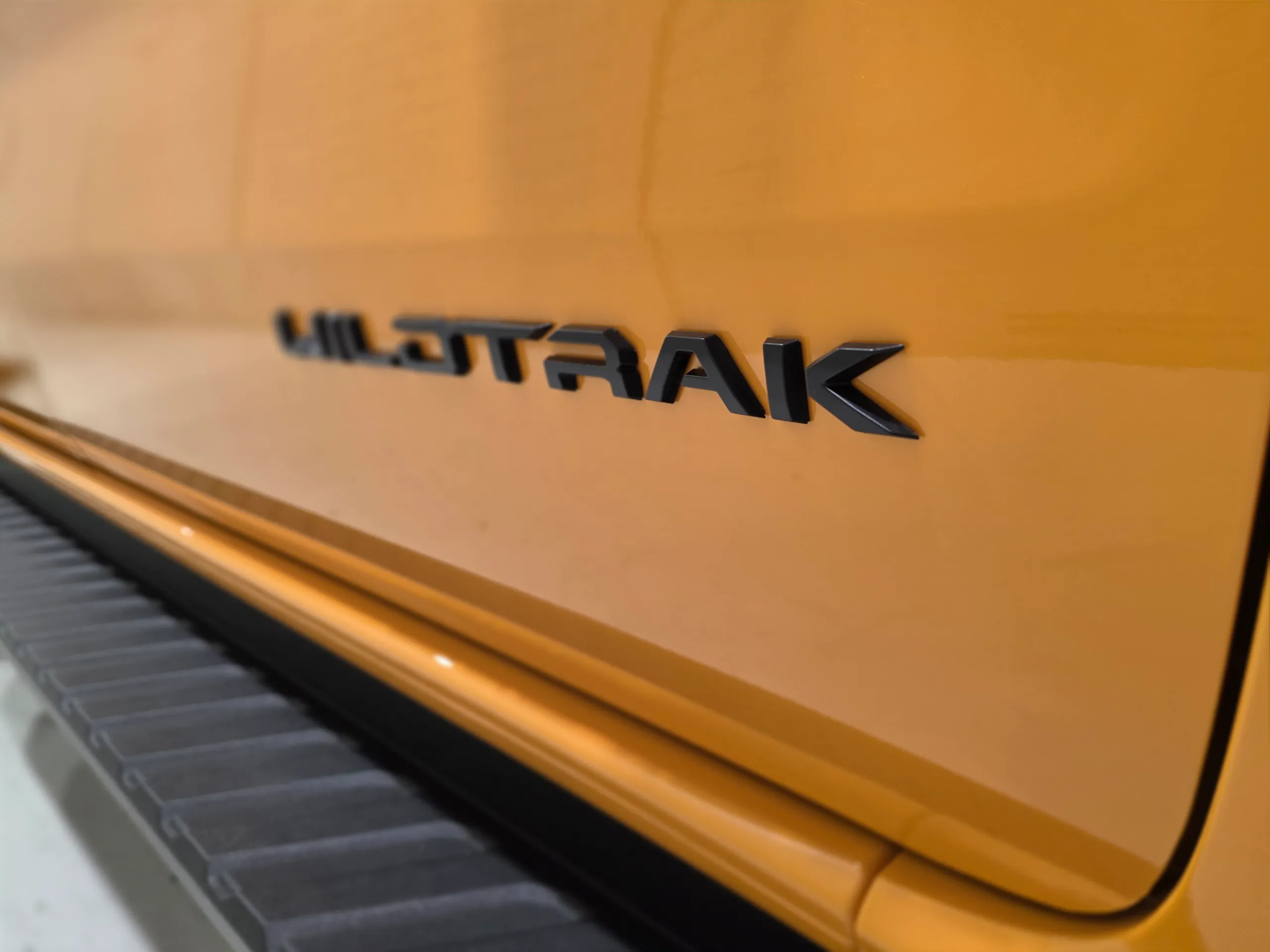 Close-up of the black Wildtrak badge on the orange Ford Ranger door