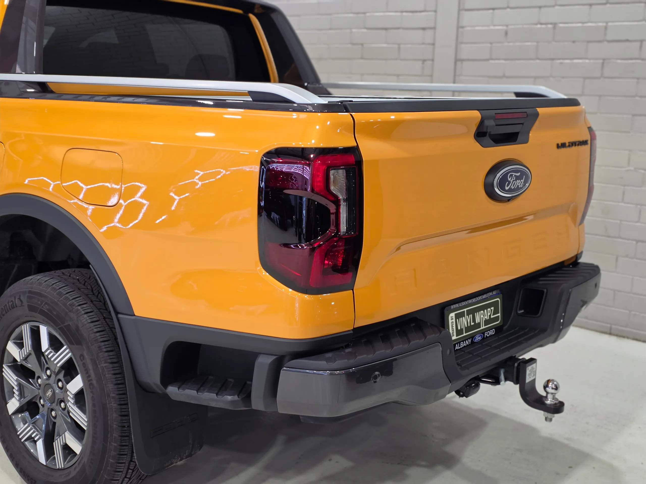 Orange Ford Ranger rear quarter showing its tailgate, rear wheel and tow bar