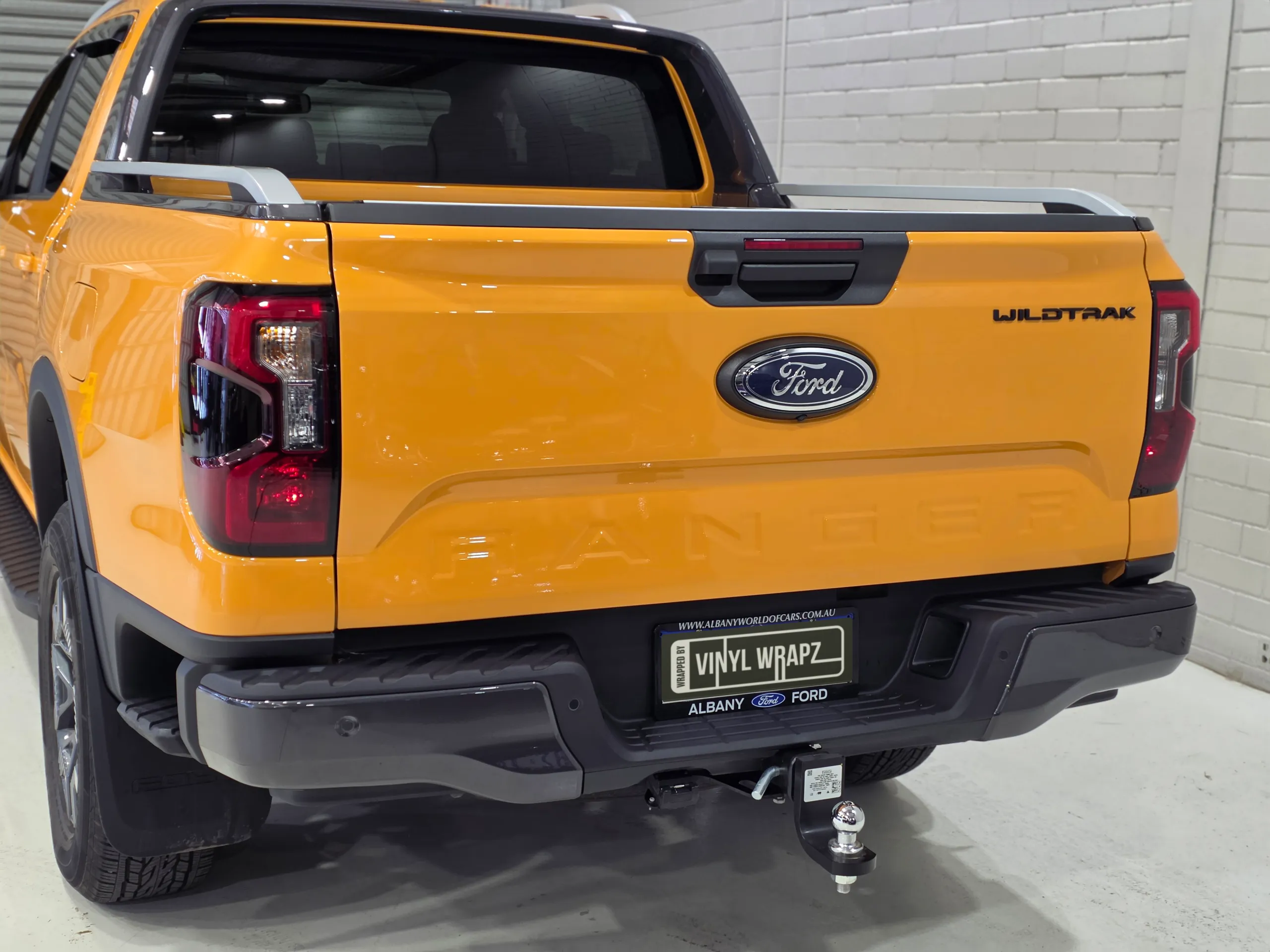 Rear view of an orange Ford Ranger Wildtrak, showing the tailgate, bumper and tow bar