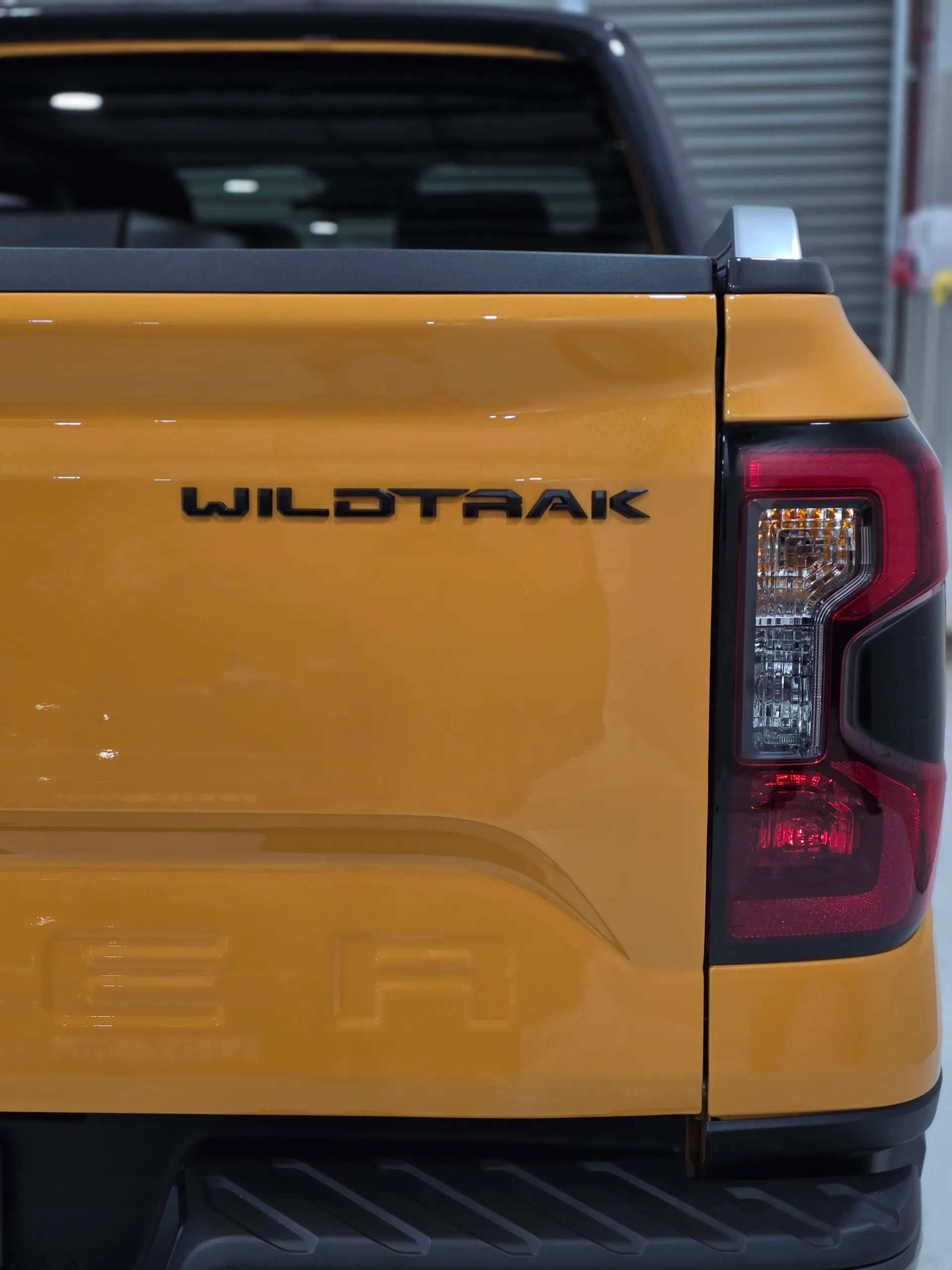 Wildtrak badge beside the rear light on an orange Ford Ranger tailgate