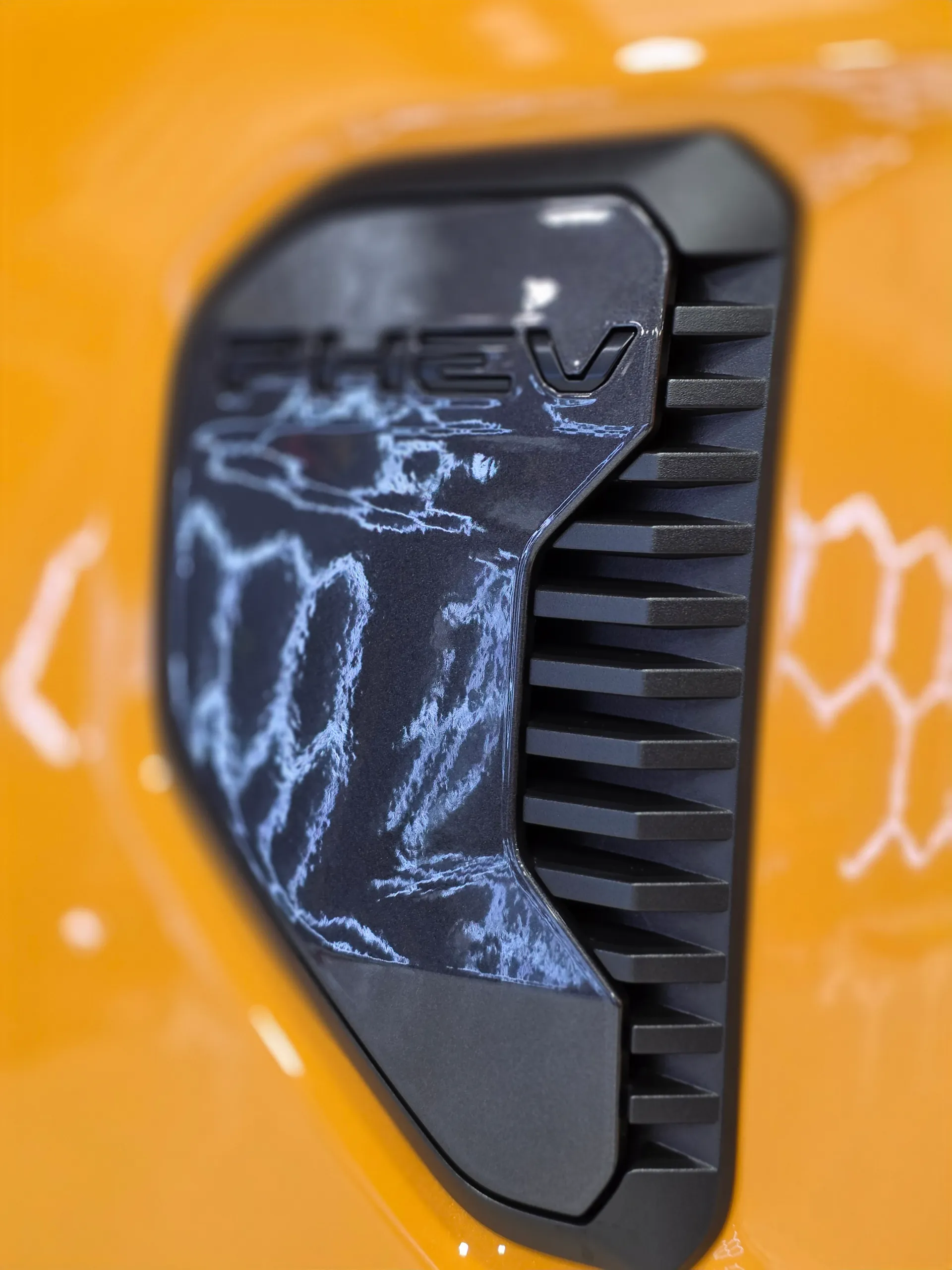 Close-up of the black PHEV trim on an orange Ford Ranger front guard