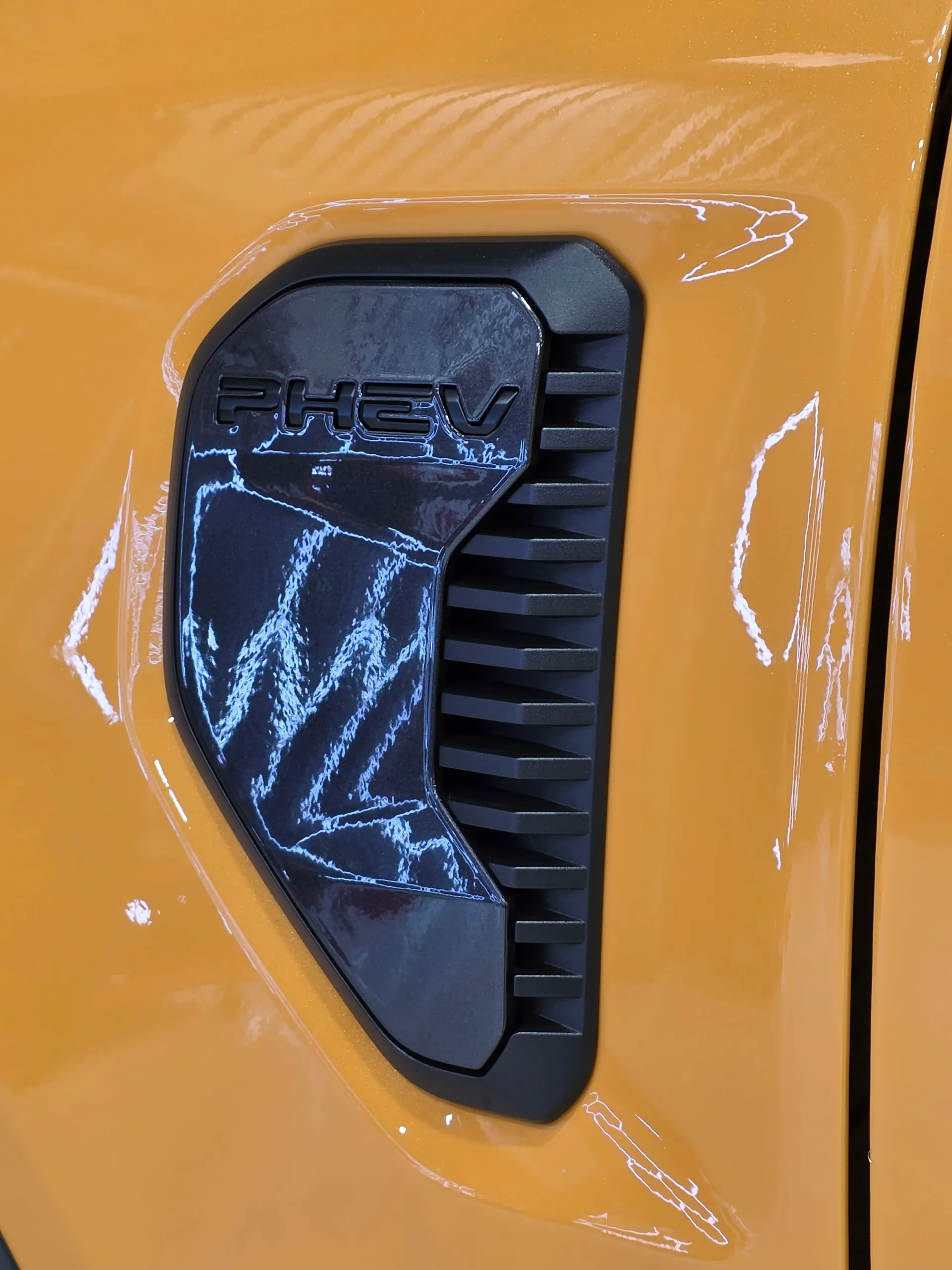 PHEV badge and black vent-shaped trim on the orange Ford Ranger front guard