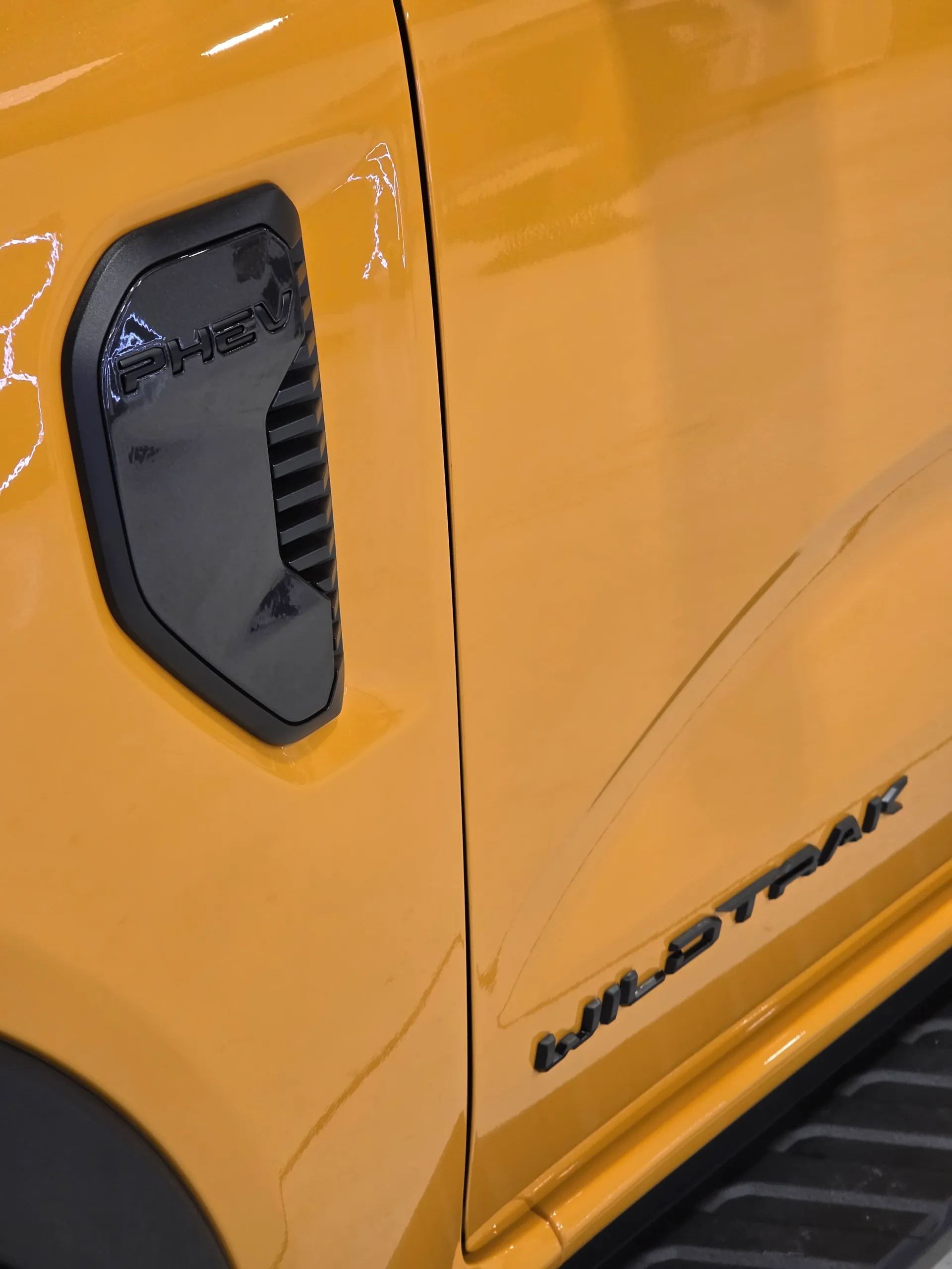 Orange Ford Ranger front guard and door showing the PHEV and Wildtrak badges