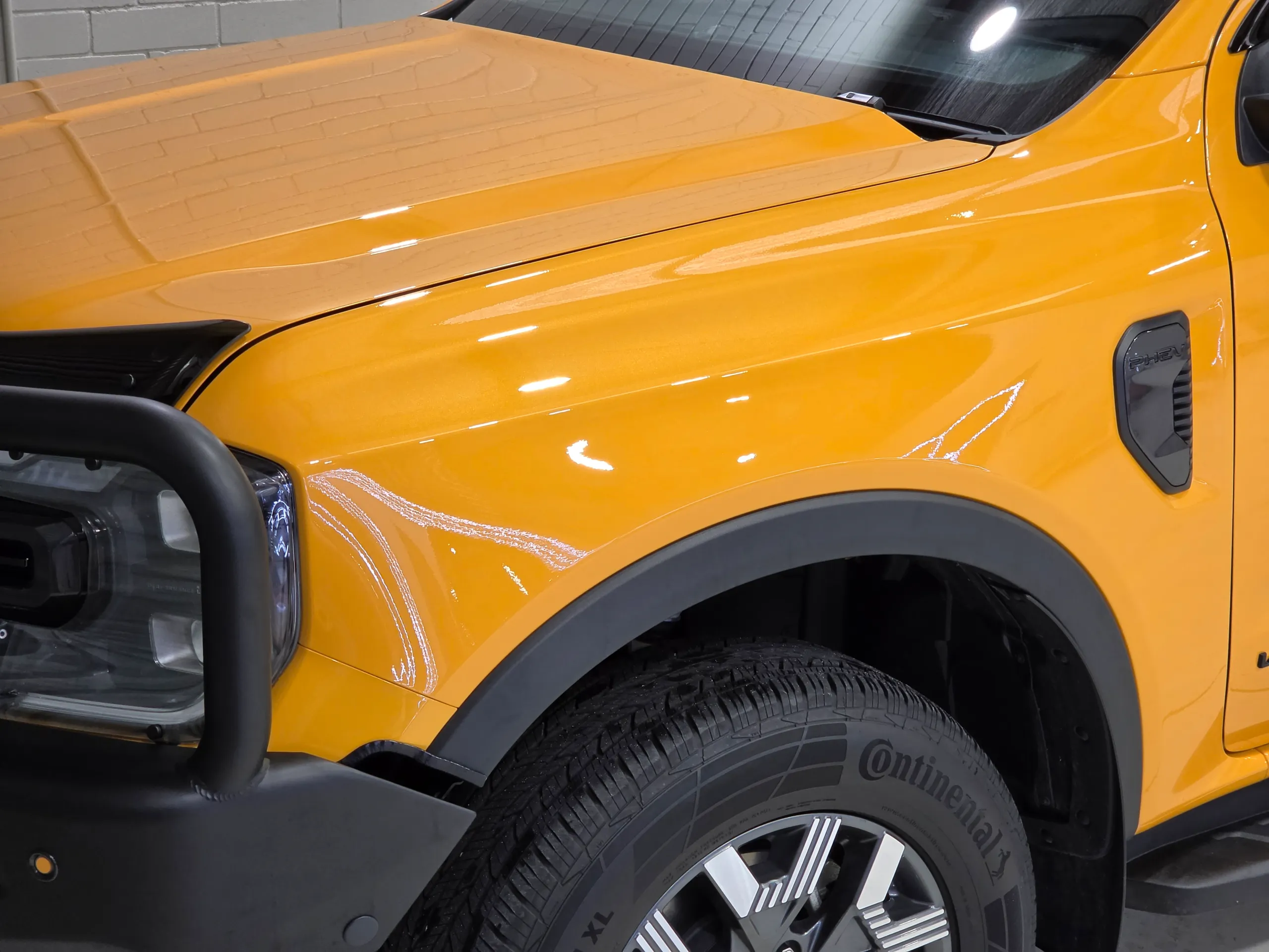 Gloss orange Ford Ranger front guard and bonnet, with the wheel and bull bar partly visible