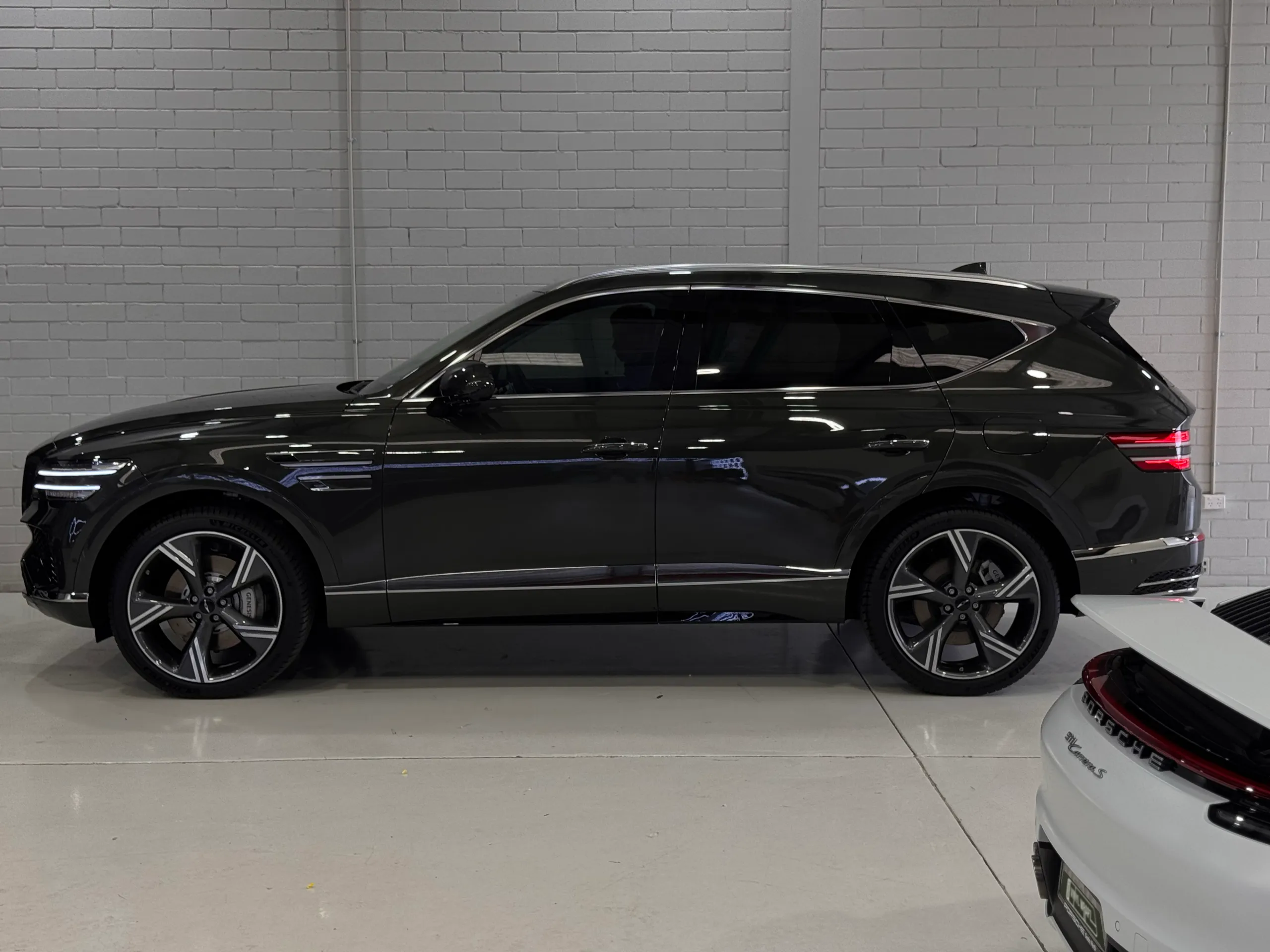 Full side profile of a gloss dark Genesis GV80 in the workshop