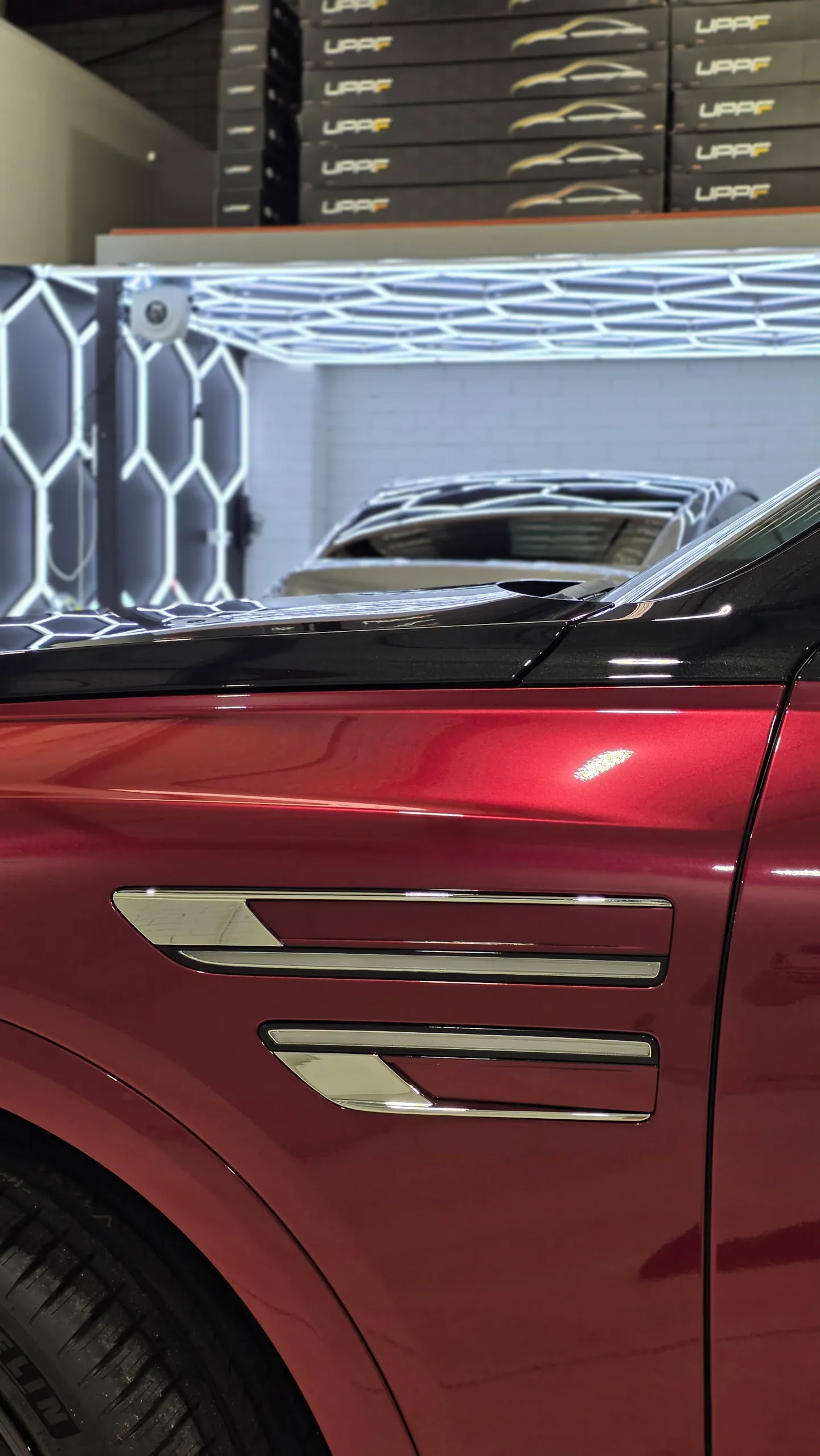 Chrome side trim against the red front guard of a Genesis GV80 Coupe