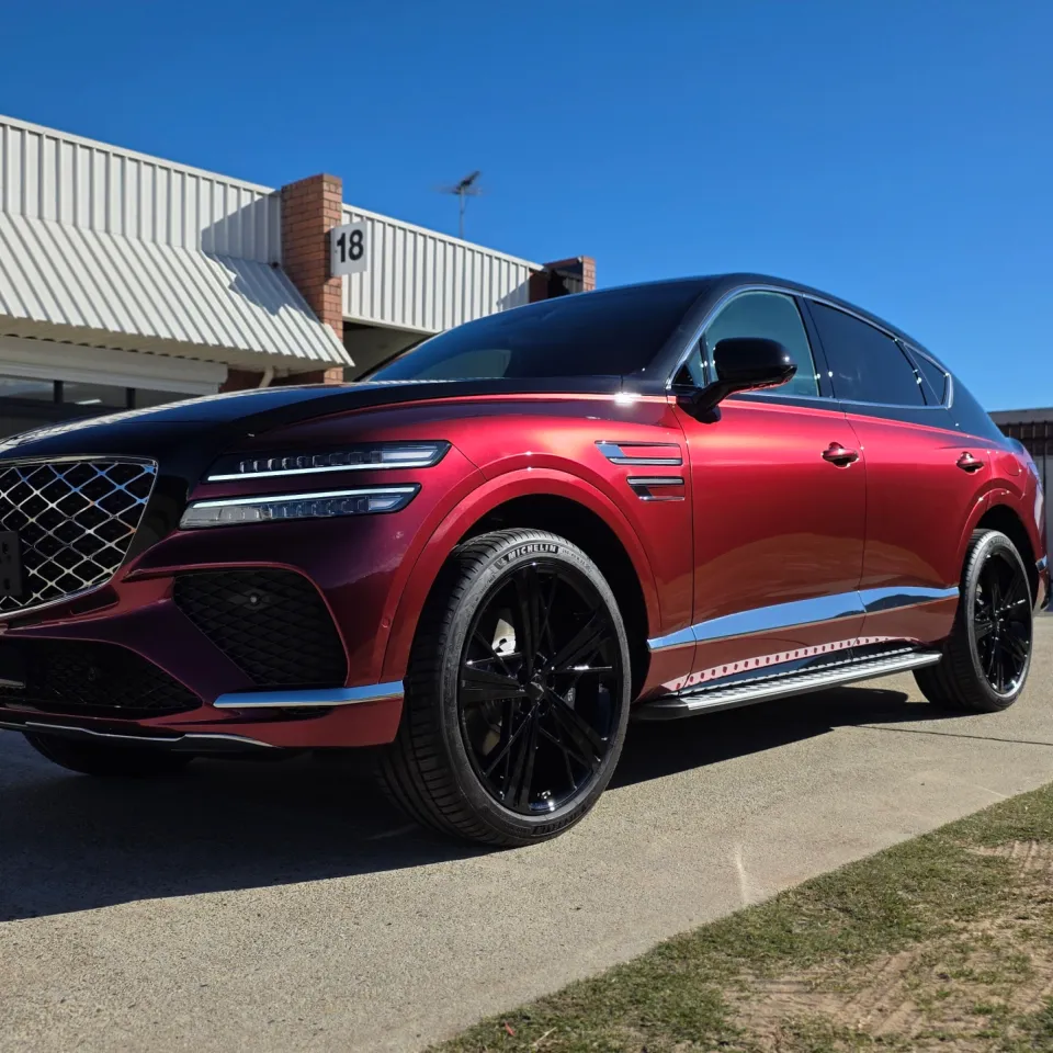 Red and black Genesis GV80 Coupe parked outside the workshop in sunlight