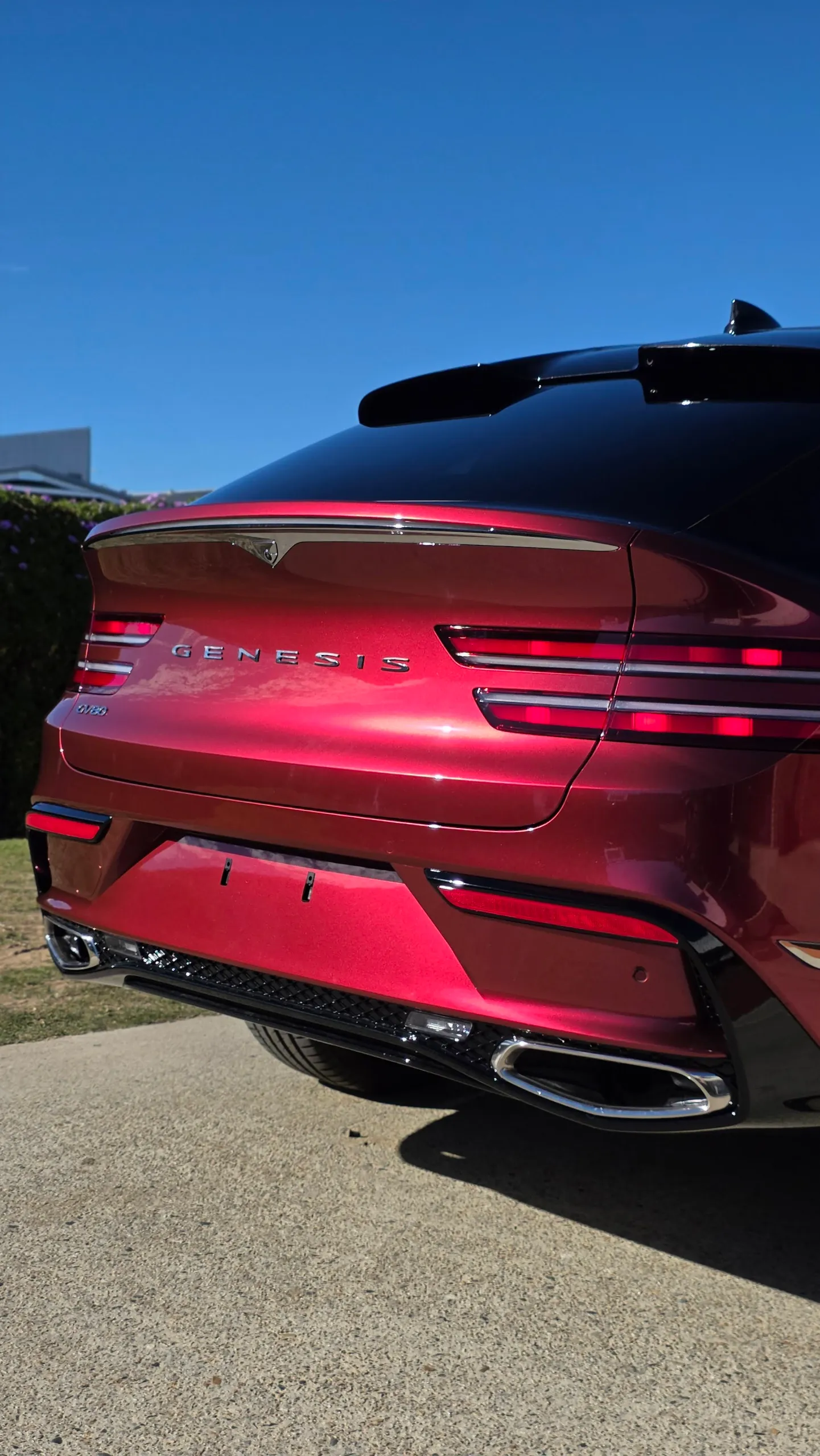 Genesis lettering, rear lights and red tailgate on a GV80 Coupe outdoors