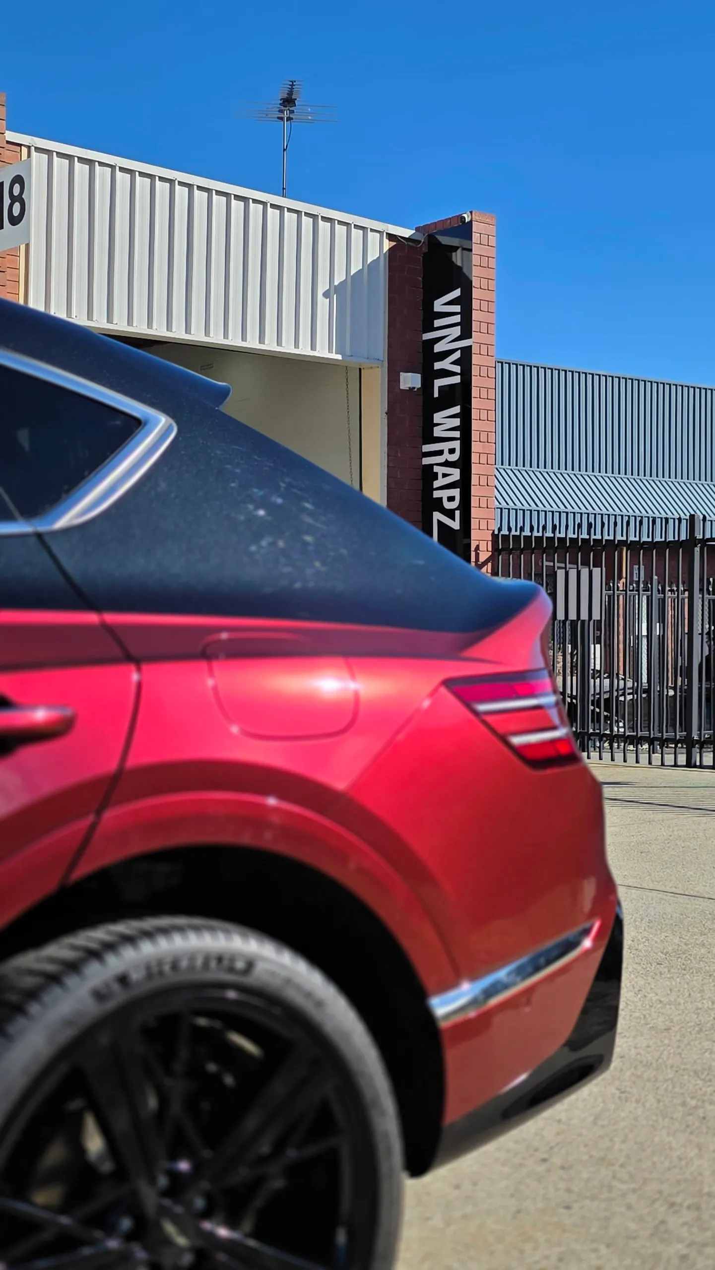 Red Genesis GV80 Coupe rear quarter and black wheel beneath the black upper body