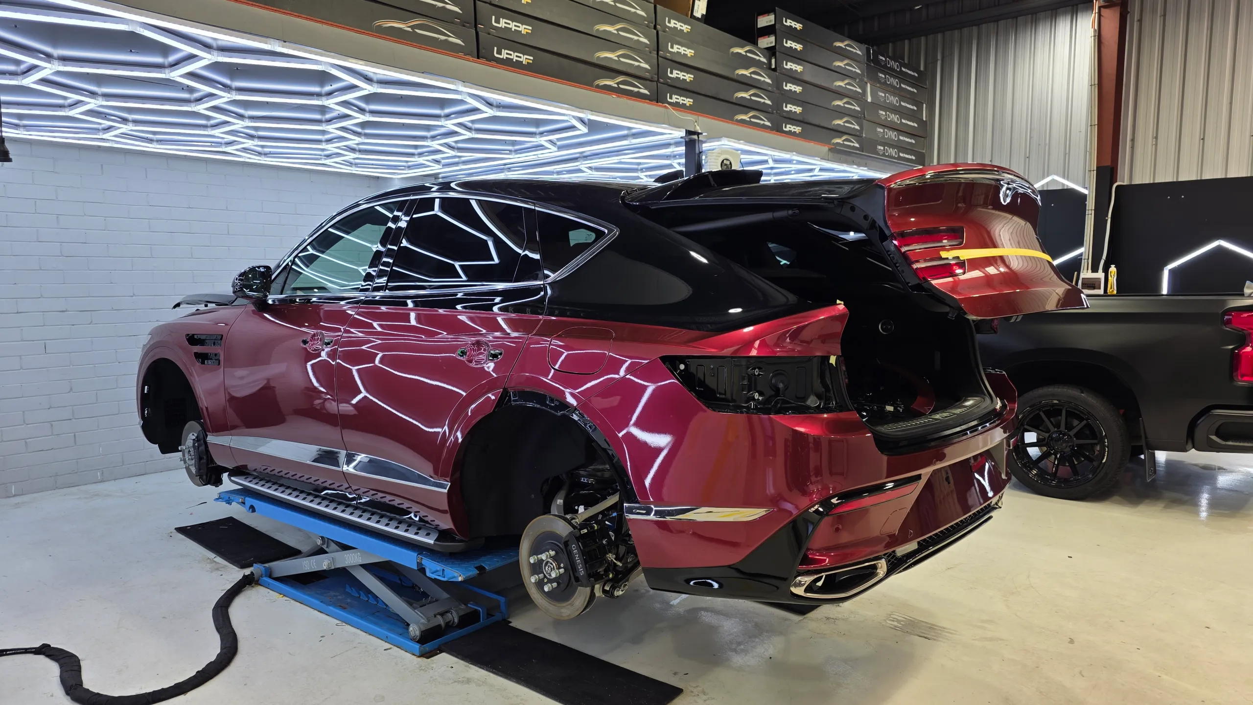 Genesis GV80 Coupe on a lift with wheels and rear lights removed during colour-change work