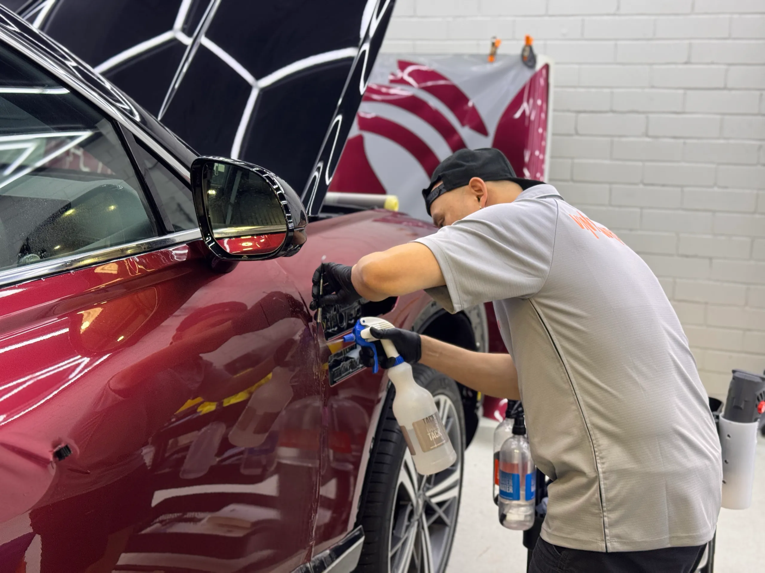 Installer working around the Genesis GV80 Coupe front guard vent during colour-change work