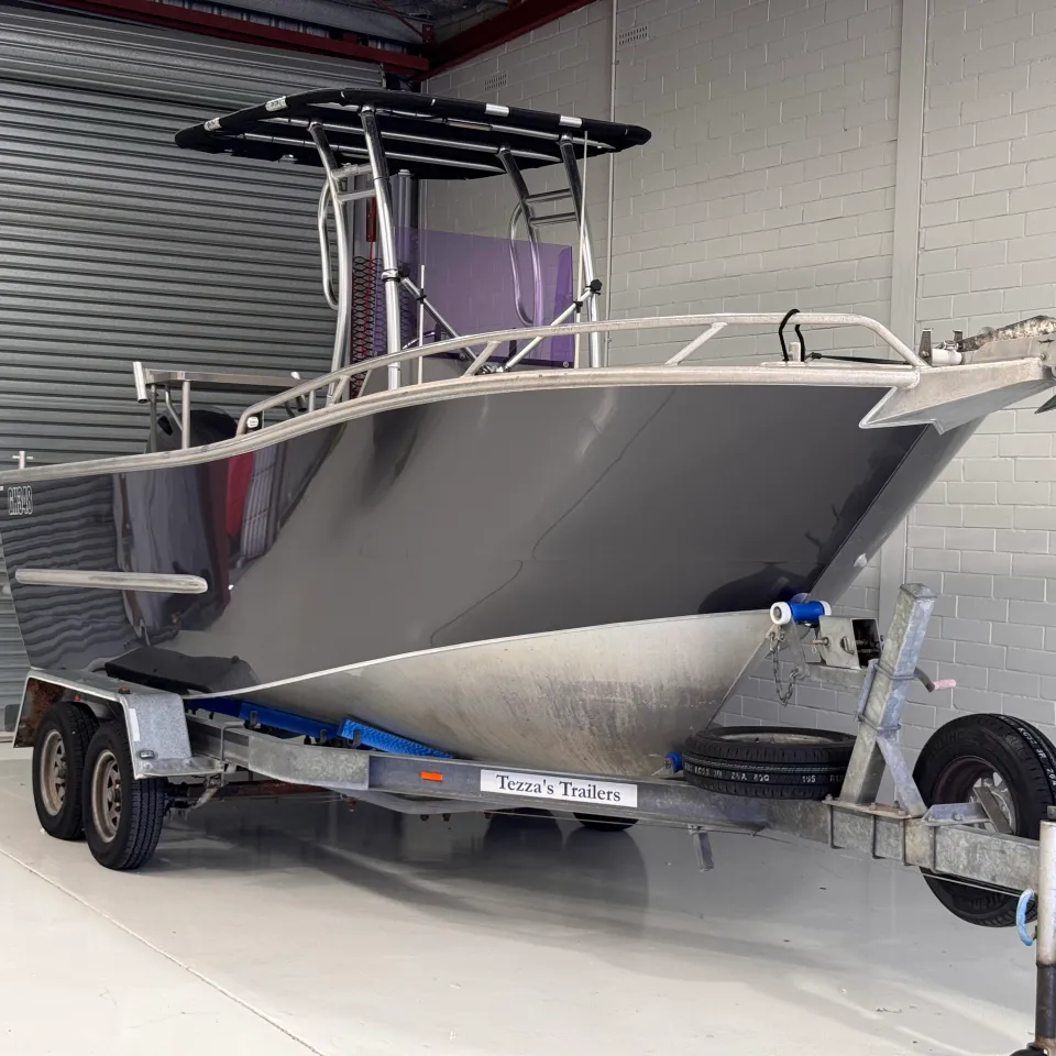 Gloss grey aluminium boat viewed from the bow quarter inside the workshop