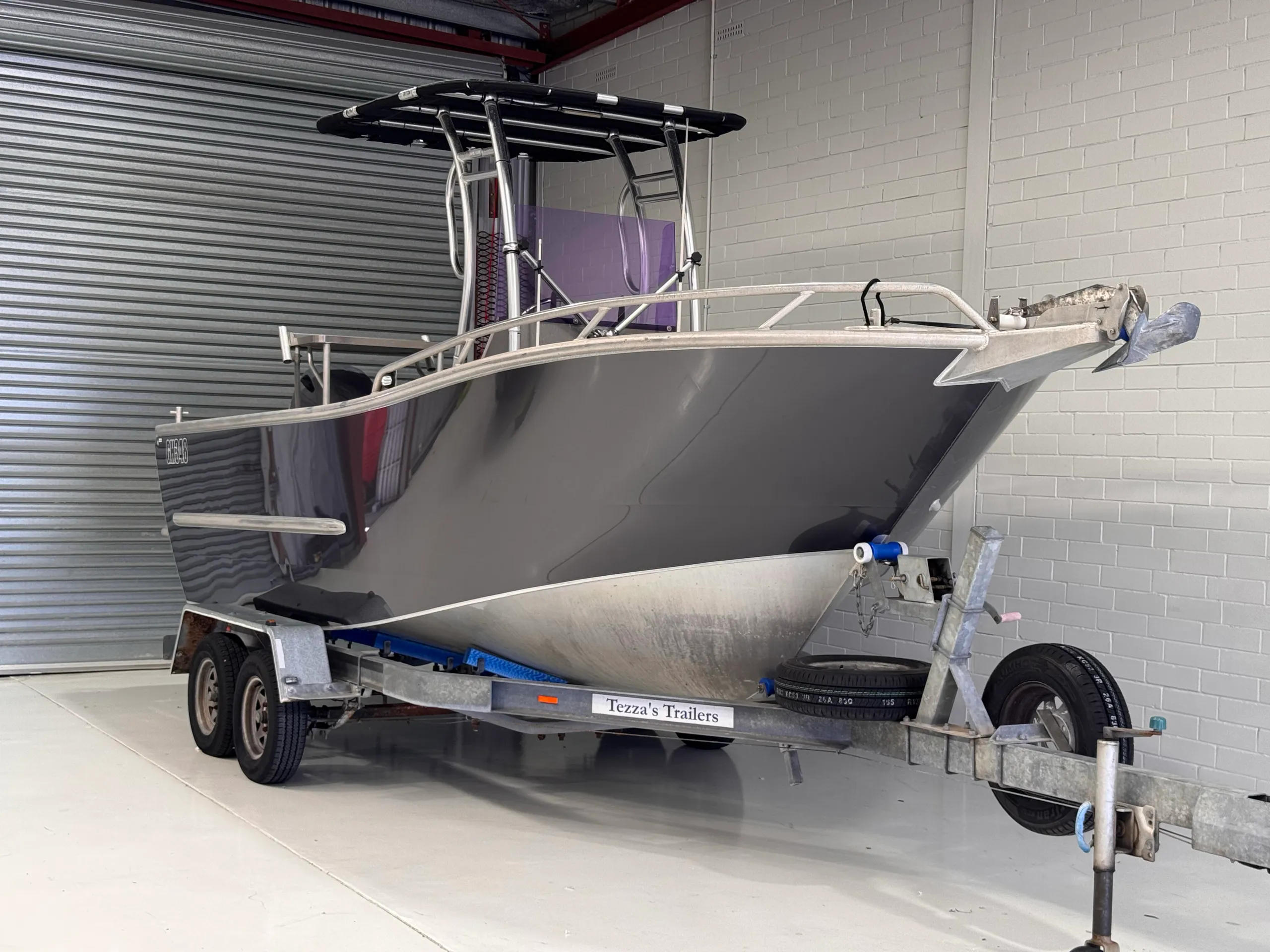 Gloss grey aluminium boat viewed from the bow quarter inside the workshop