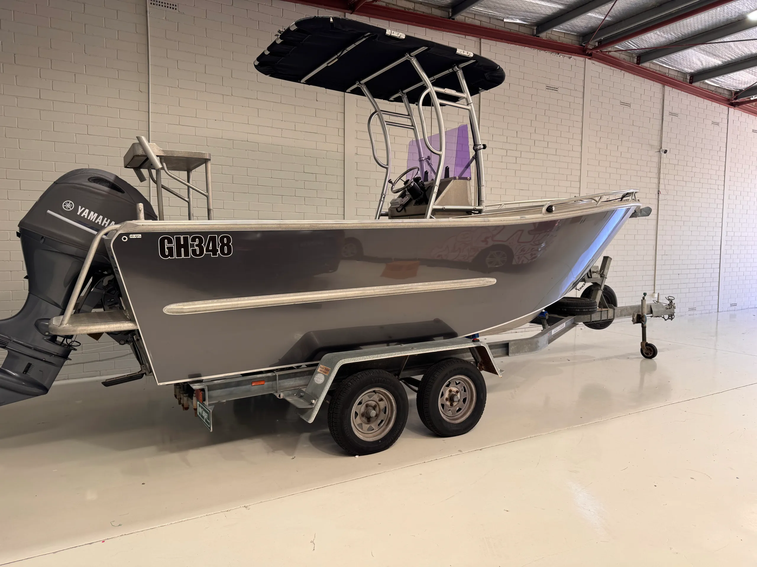 Grey aluminium centre-console boat with a Yamaha outboard on its trailer inside the workshop