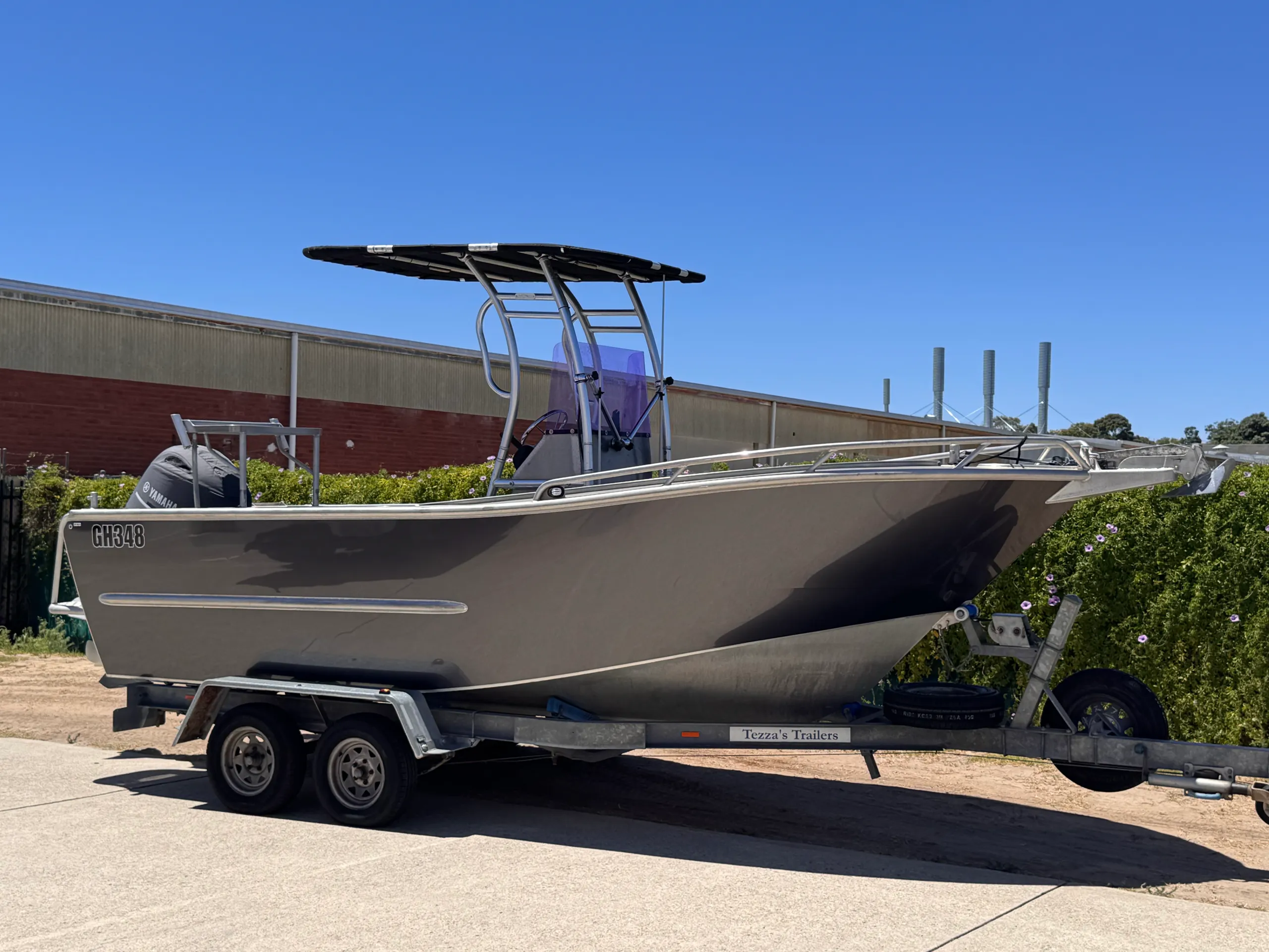Gloss grey aluminium centre-console boat on its trailer outside the workshop