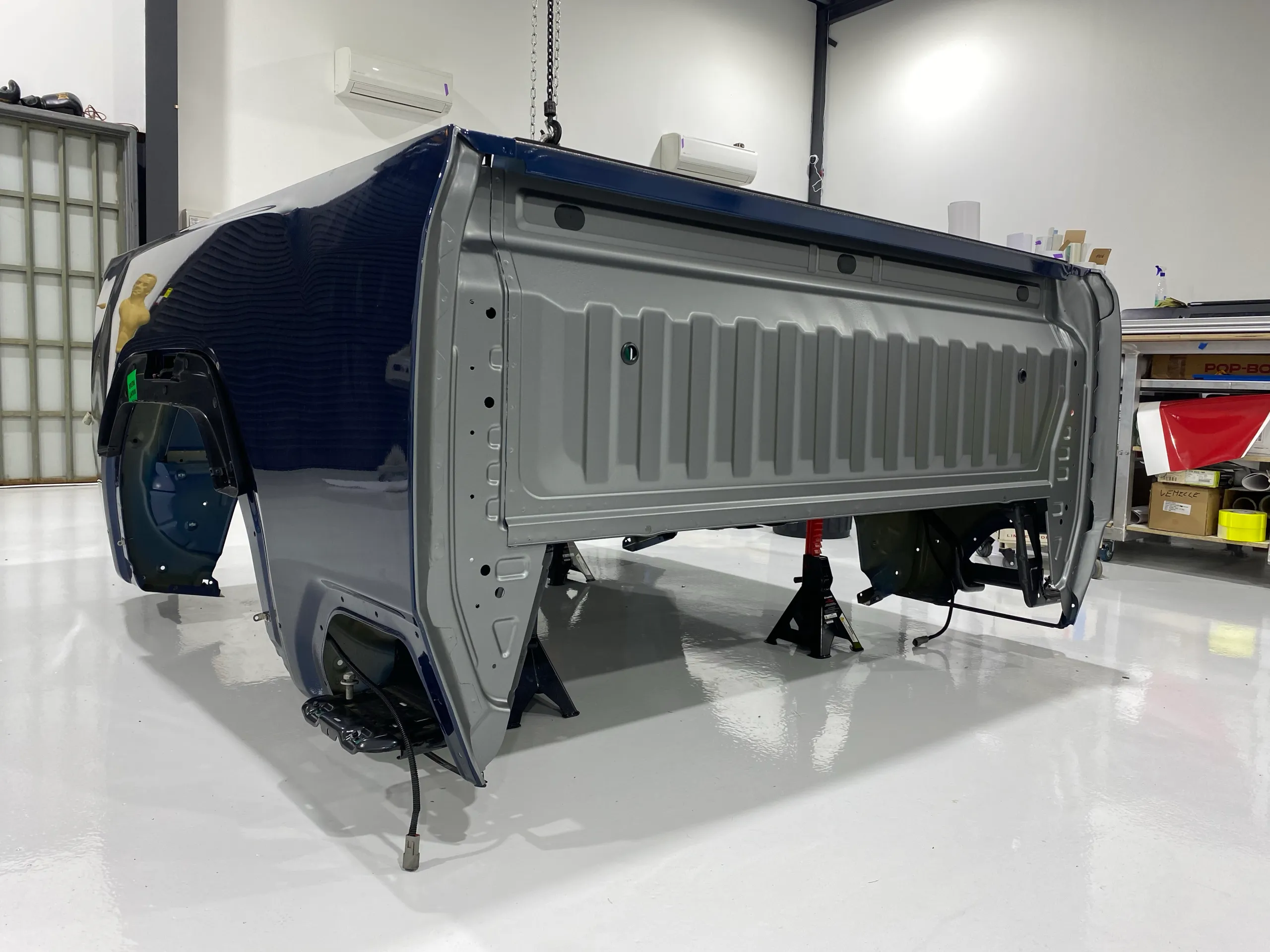 Removed GMC pickup bed on stands with original dark blue paint beside grey-wrapped areas