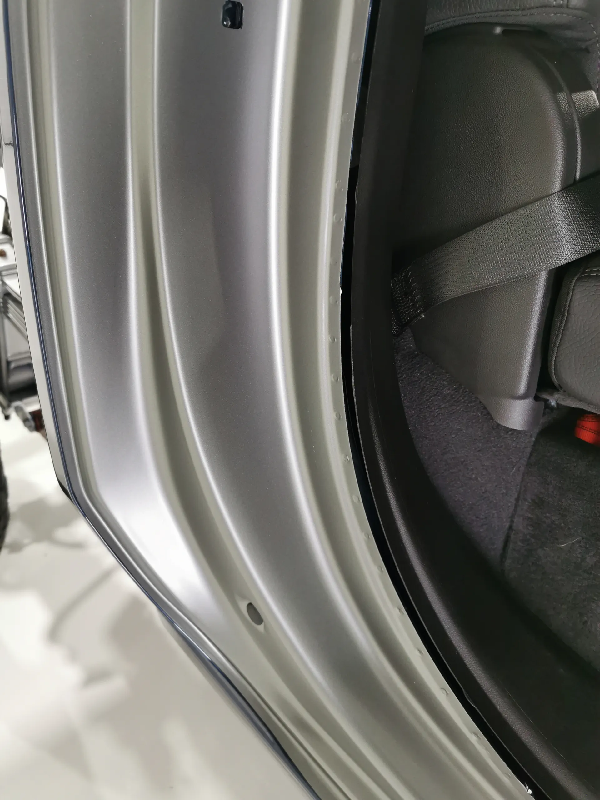 Grey wrap around the GMC cab door opening beside the seat and seatbelt