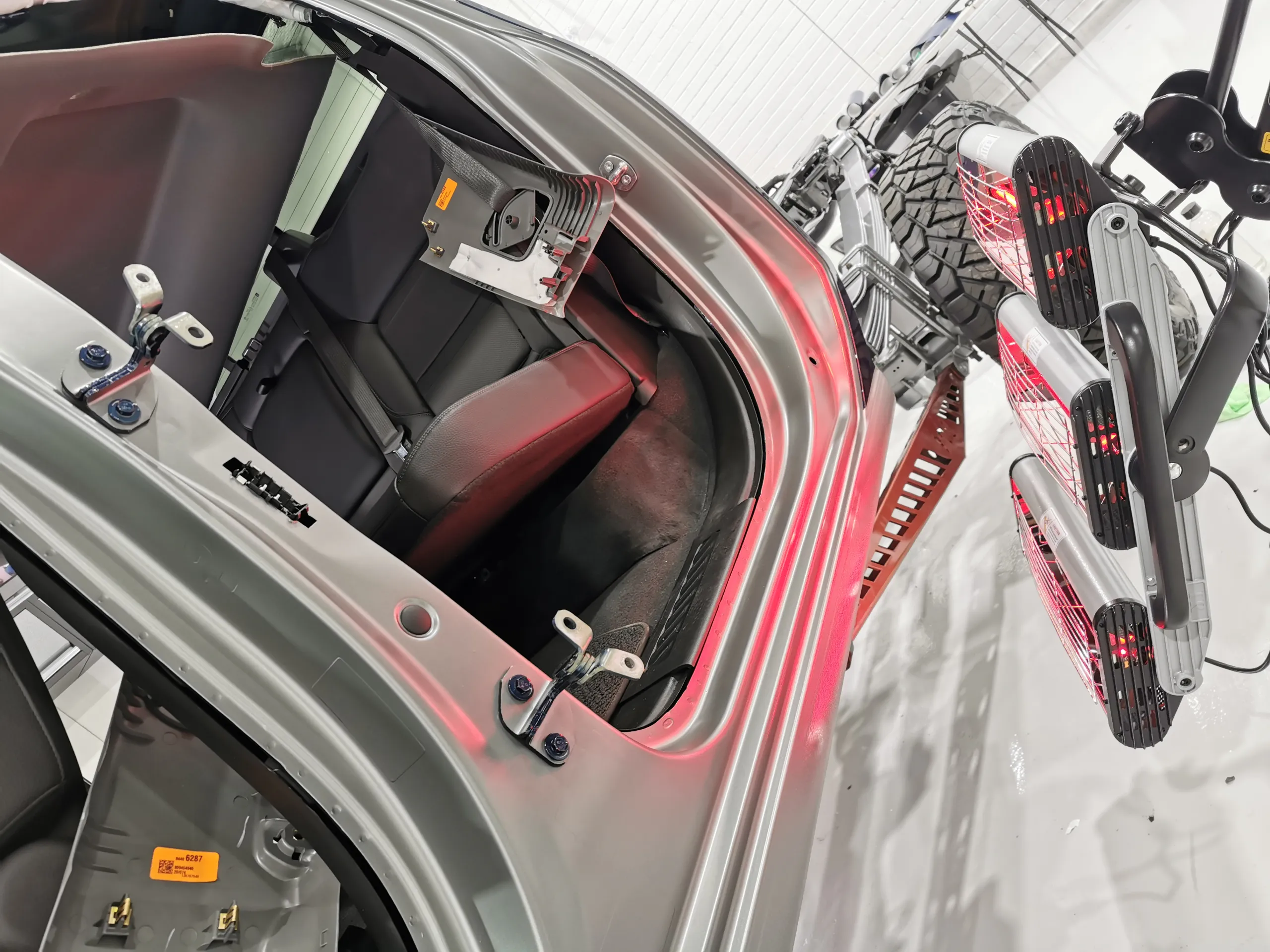 Infrared lamps heating grey film around the GMC cab opening with the doors removed