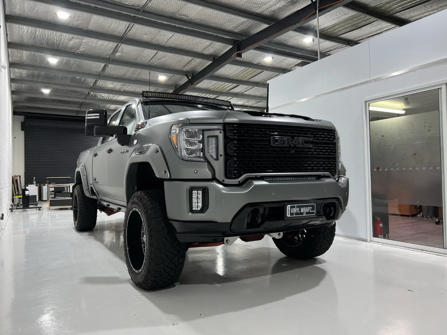 Front-quarter view of the lifted satin grey GMC Sierra Denali with black wheels