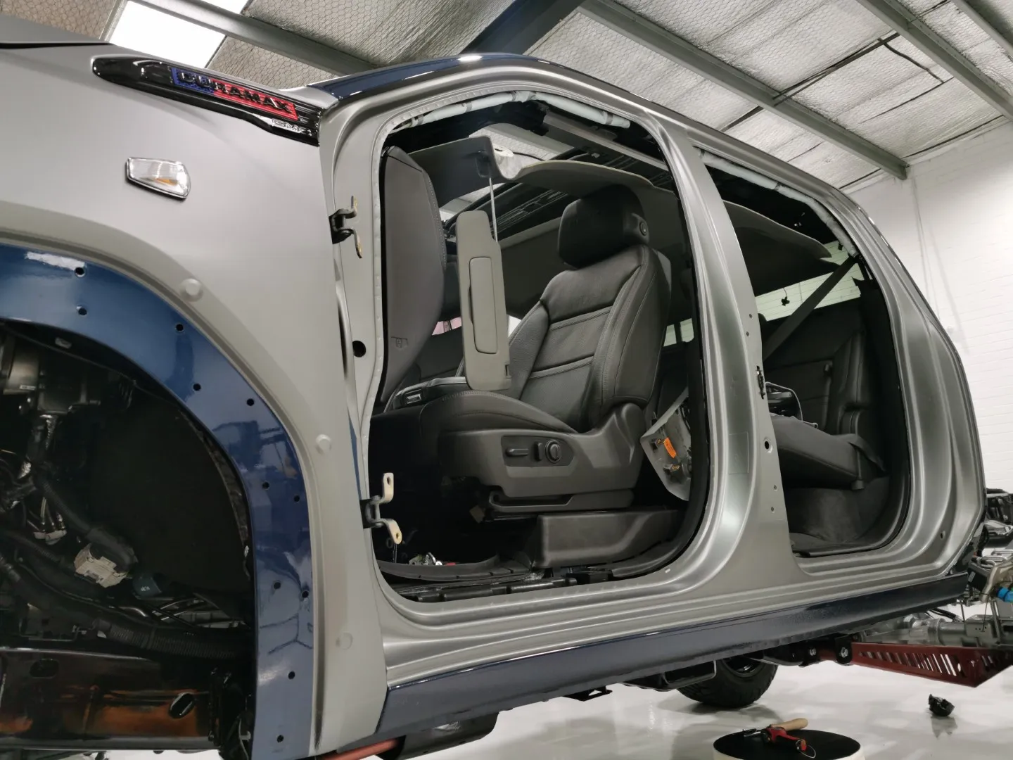 GMC cab during wrapping with doors and wheel-arch trim removed, exposing original blue paint