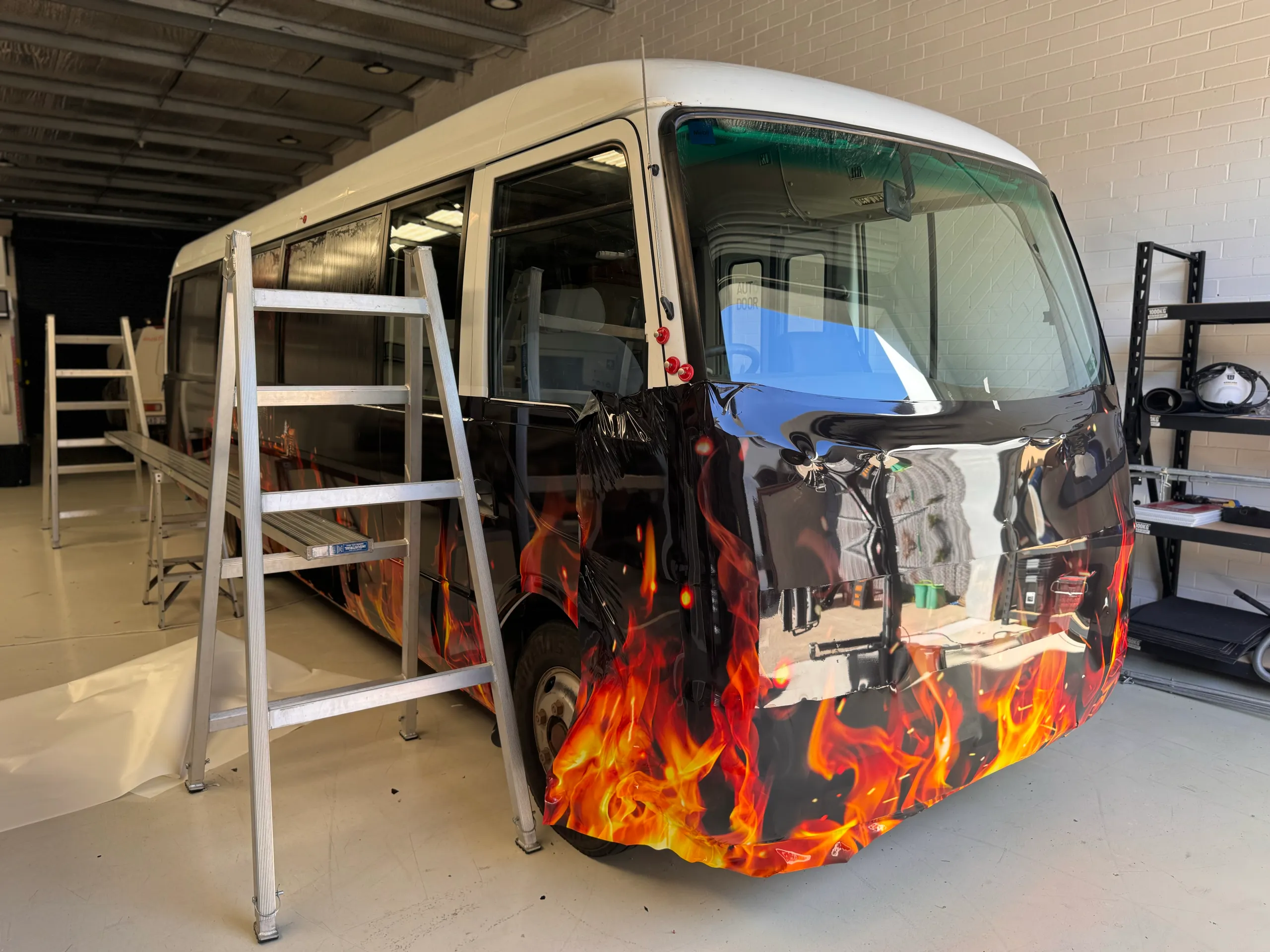 Flame graphics being fitted around the front of the Gourmet Camp Oven Experience bus
