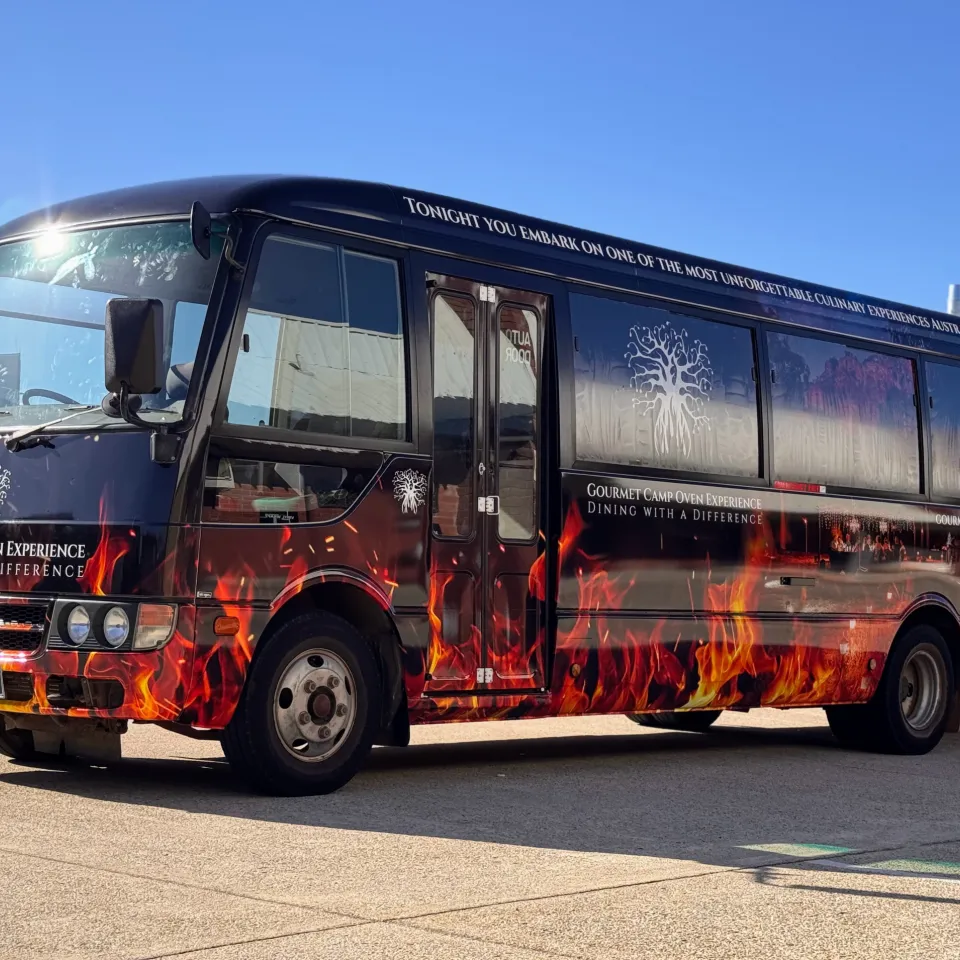 Gourmet Camp Oven Experience bus with orange flame graphics on a dark printed wrap