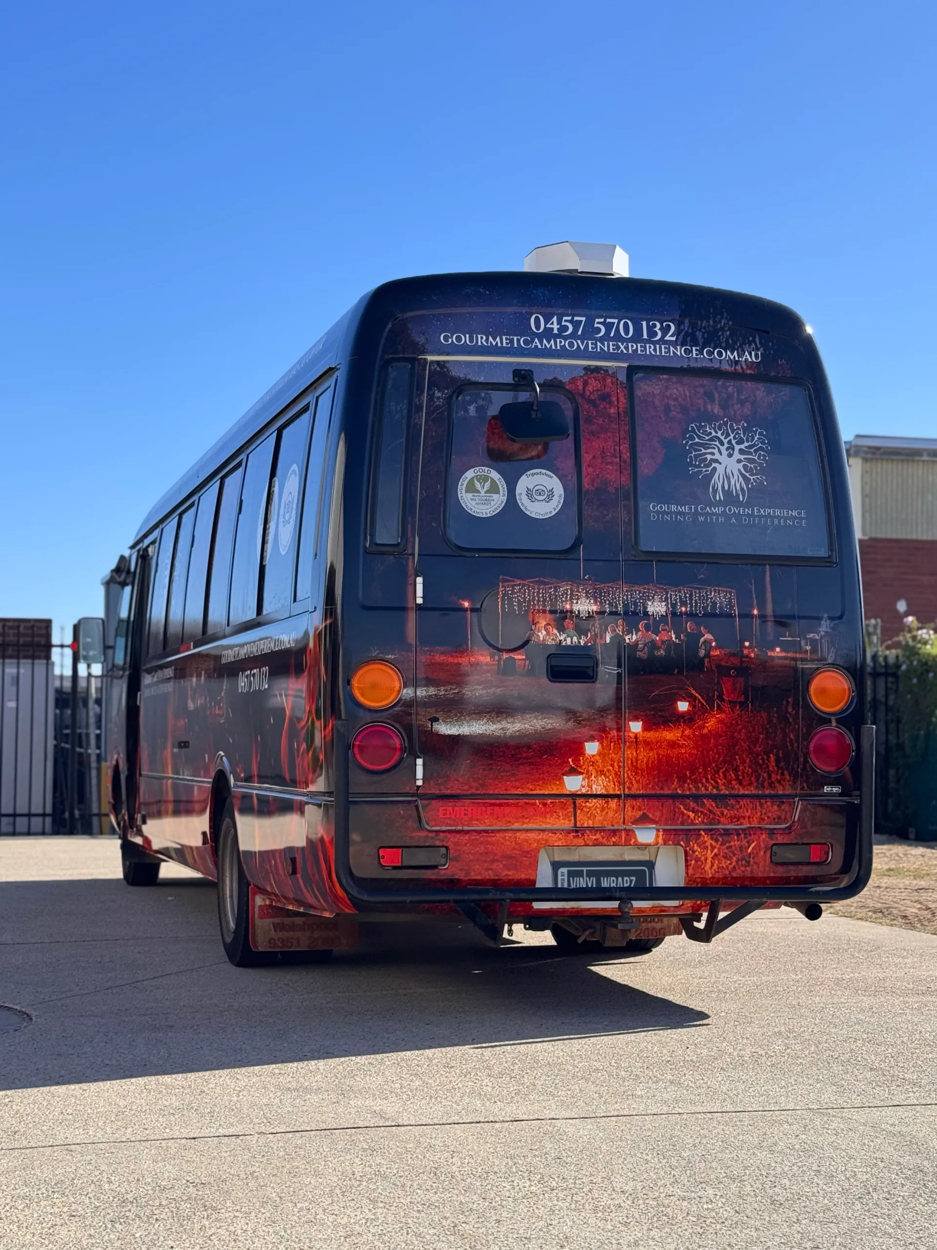 Rear view of the Gourmet Camp Oven Experience bus wrap outdoors