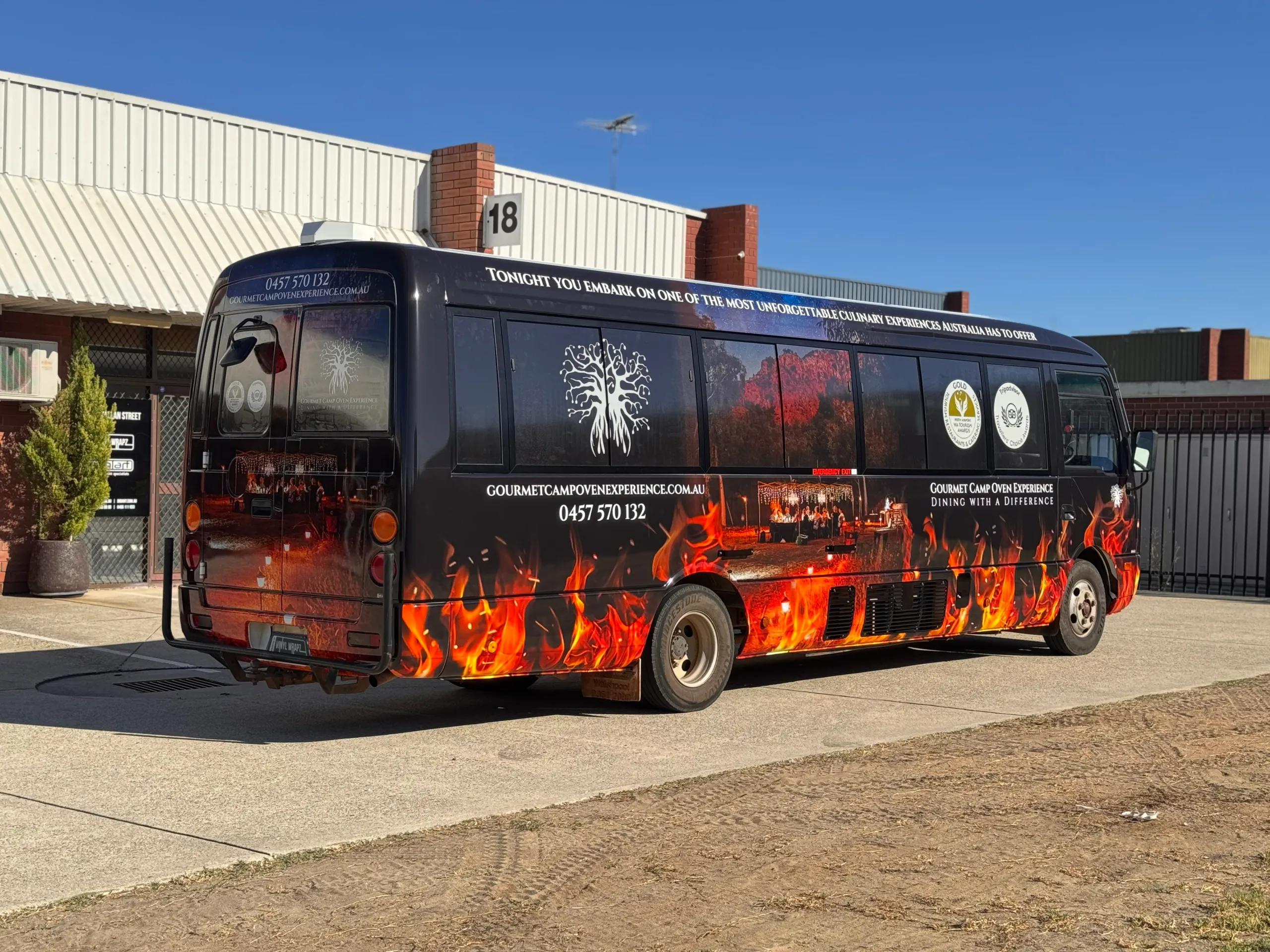 Rear-quarter view of the bus with flame graphics and dining imagery along its side