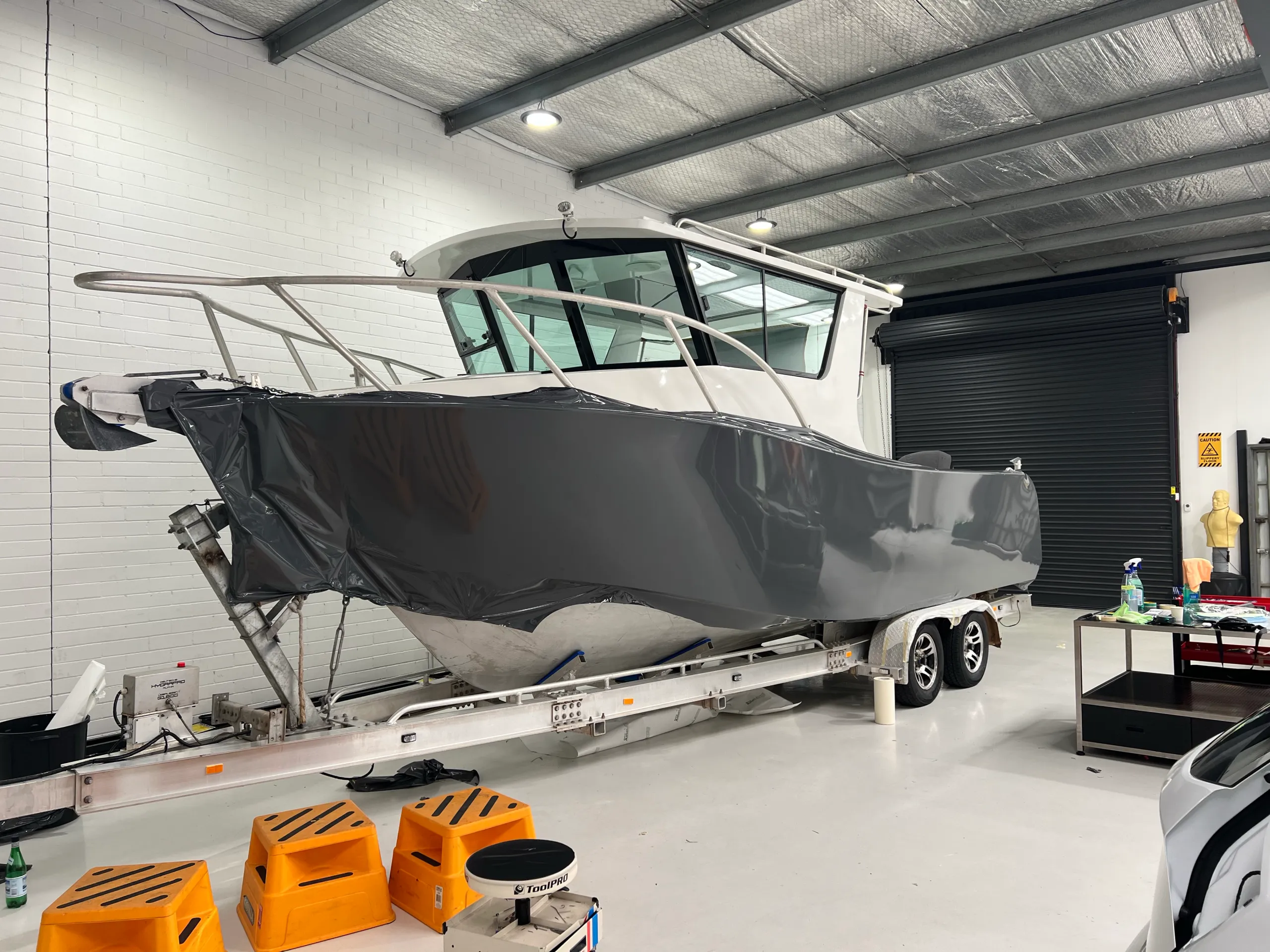 Loose grey film stretched around the bow and side of the aluminium boat