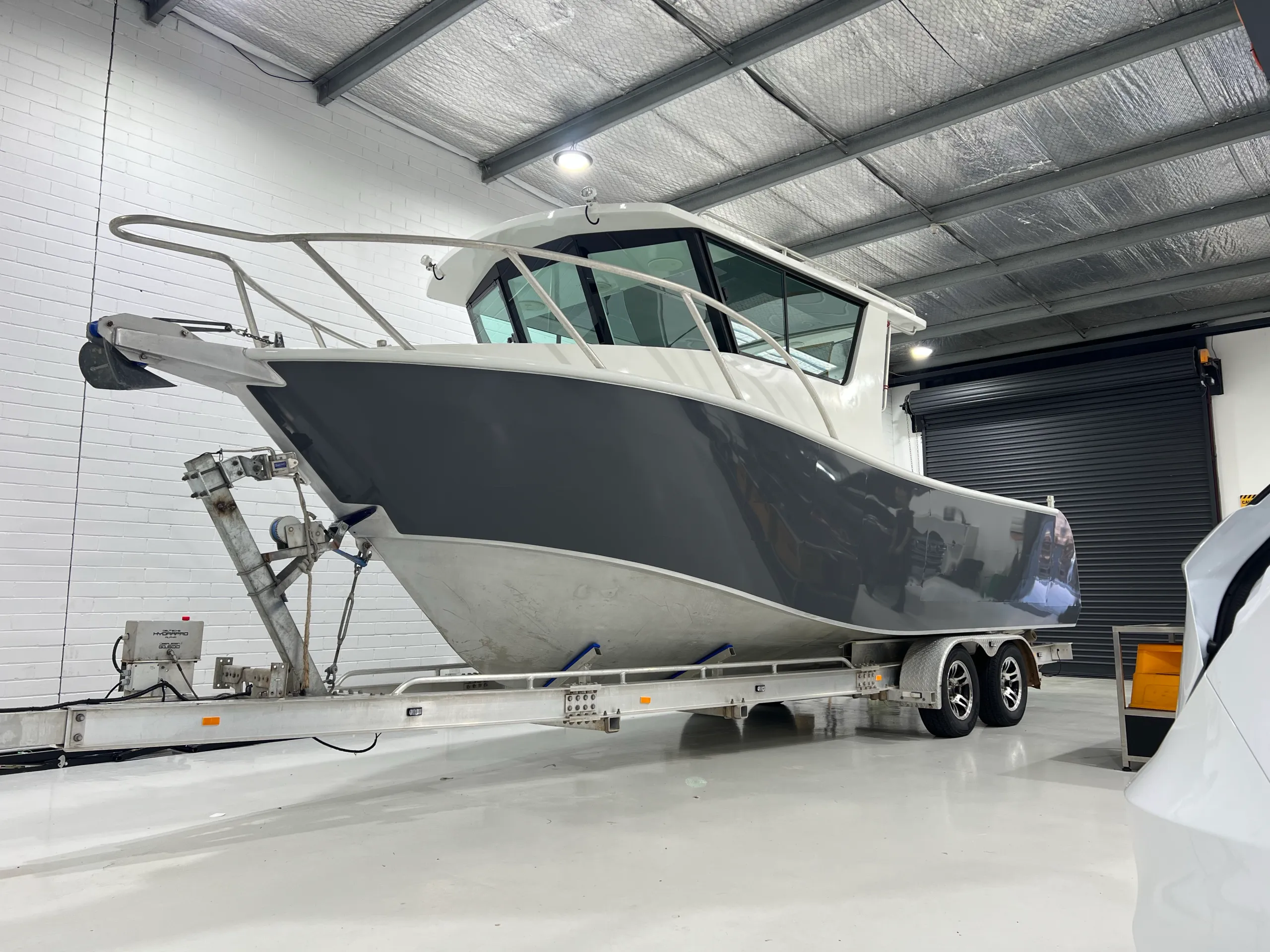 Finished grey hull and white cabin on the aluminium boat in the workshop