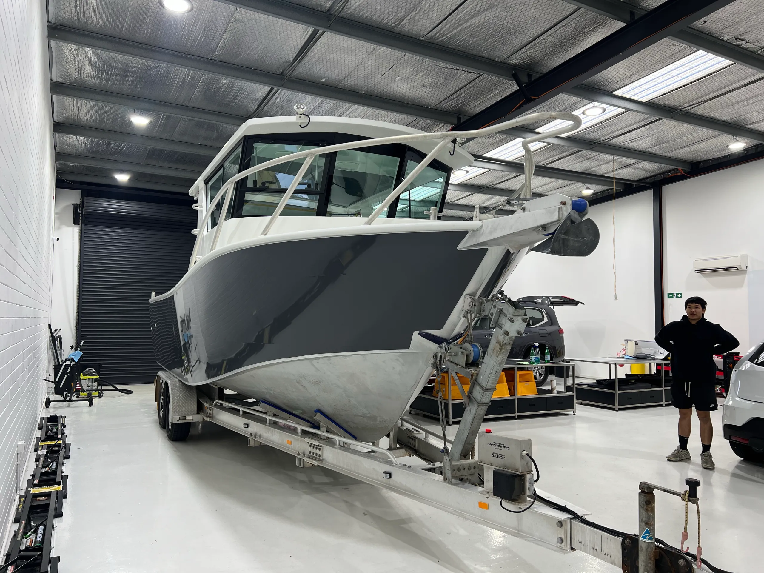 Finished grey boat bow with a person standing beside the trailer in the workshop