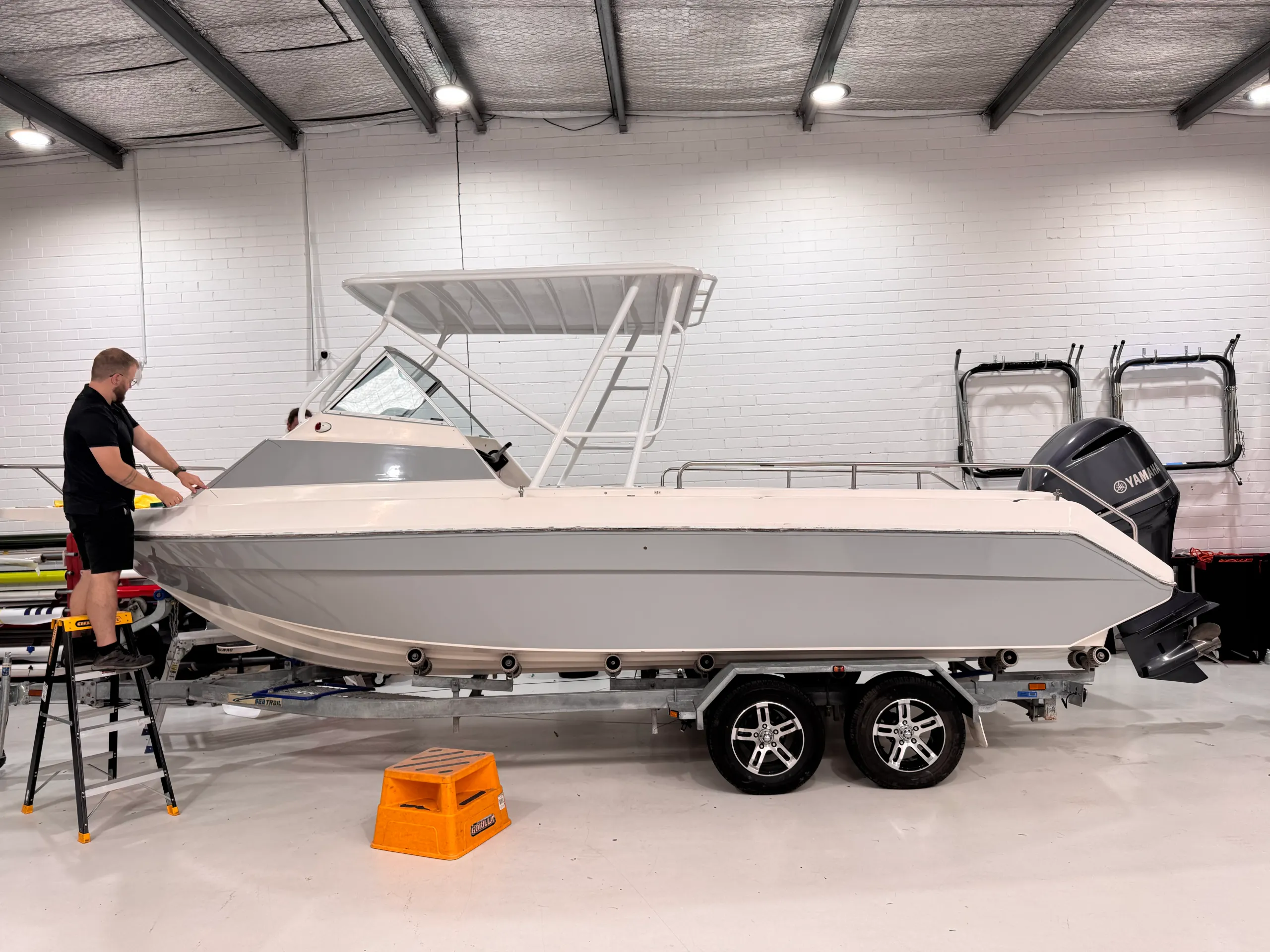 Side view of the grey boat hull during cabin wrapping in the workshop