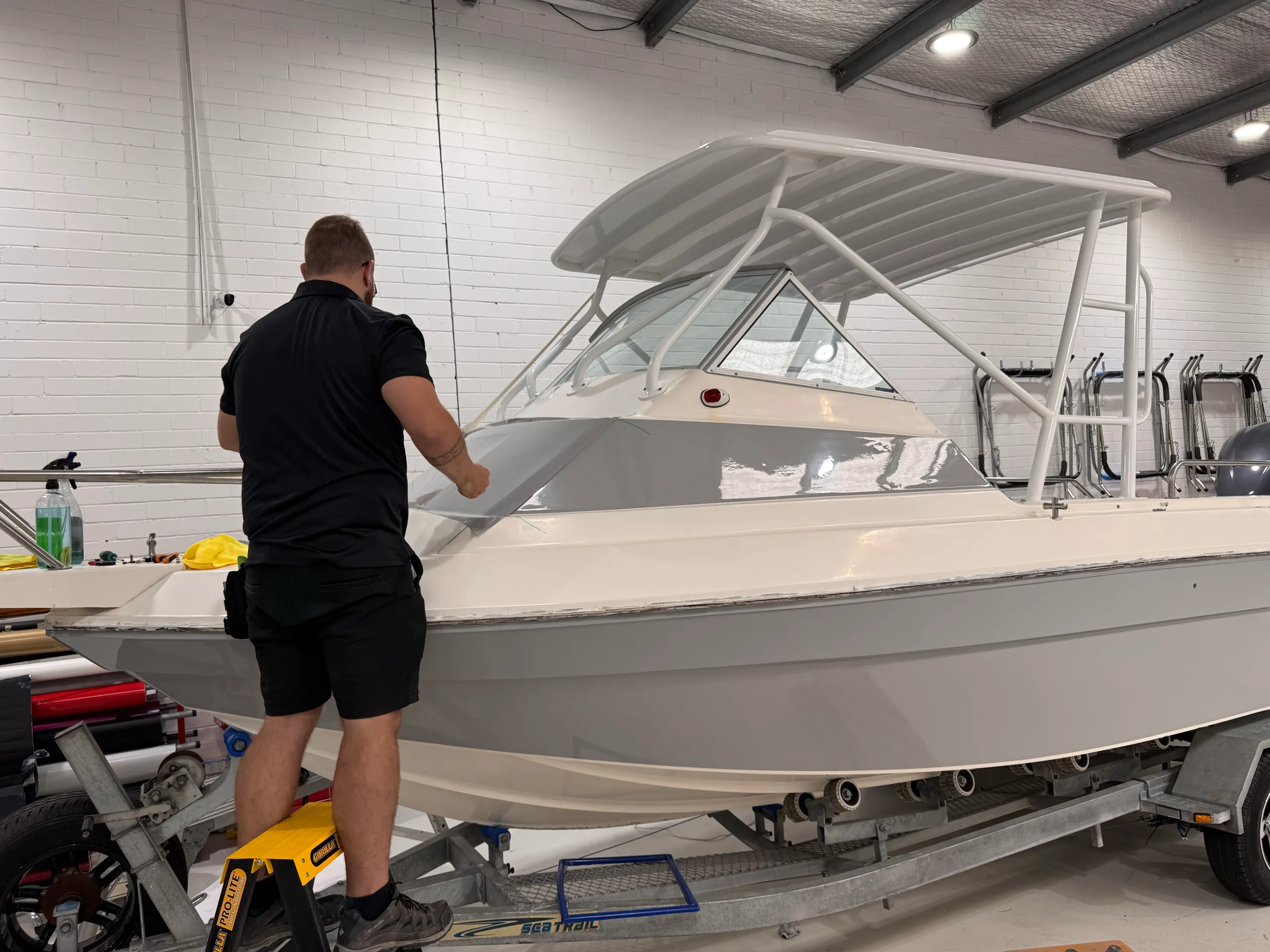 Installer facing away while fitting grey film around the boat cabin