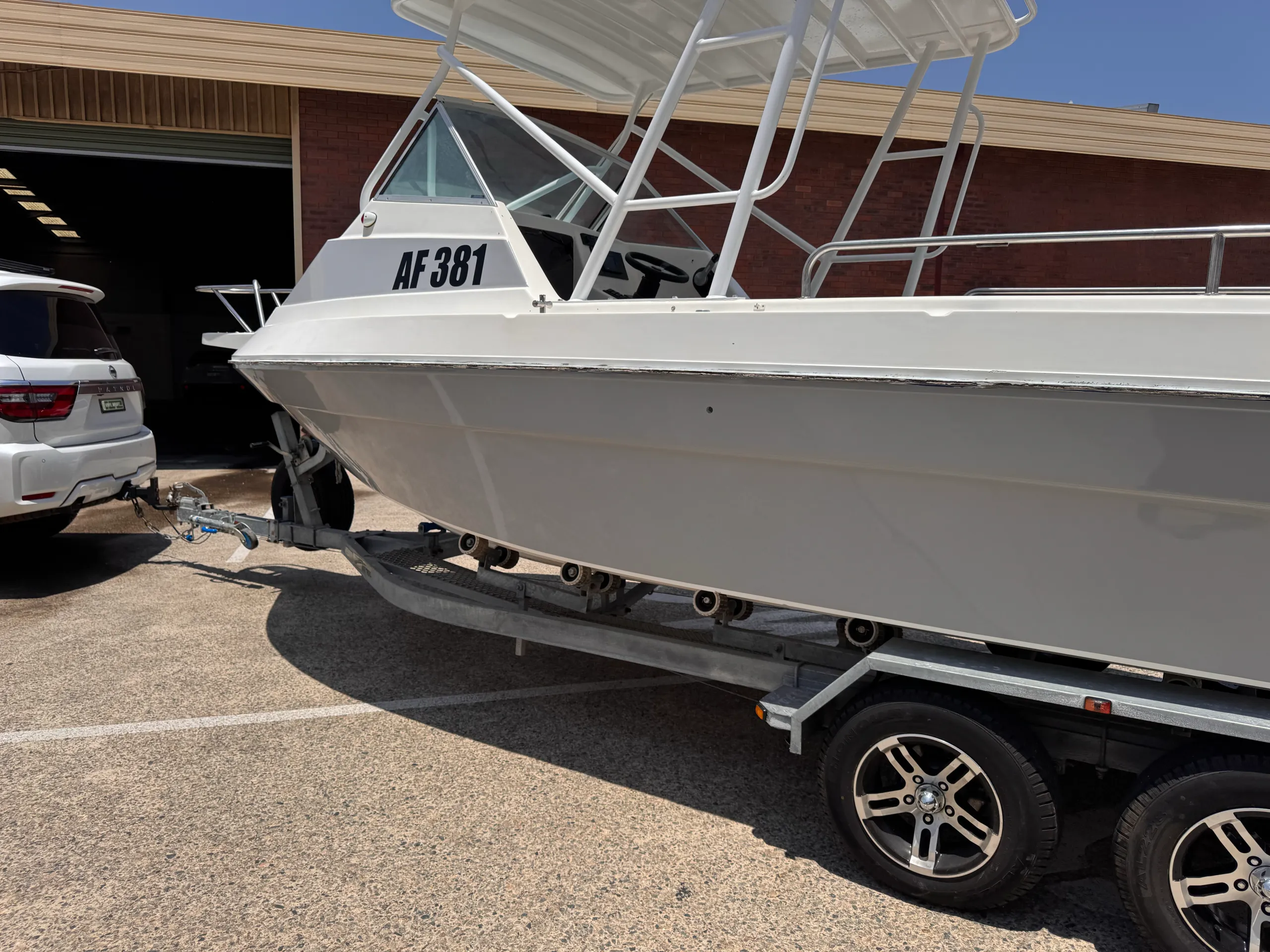 Grey wrapped boat hull beneath a white cabin outside the workshop